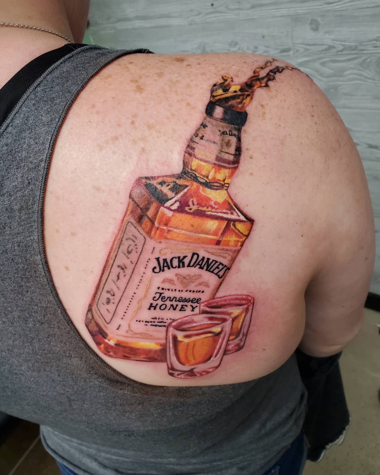 Jack Daniel's Tennessee Honey bottle realism tattoo on the back by Emily Jestine Francis