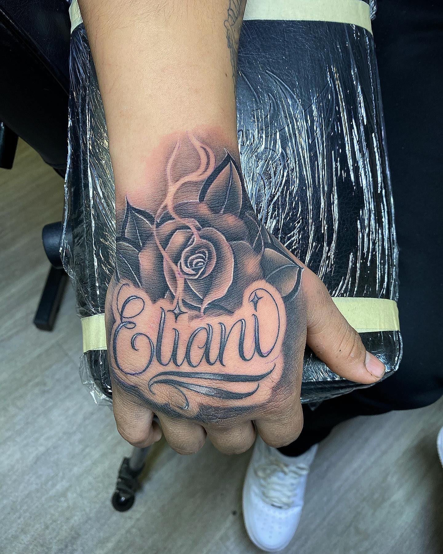 Rose with name black and grey tattoo on the hand by TattsByShorty