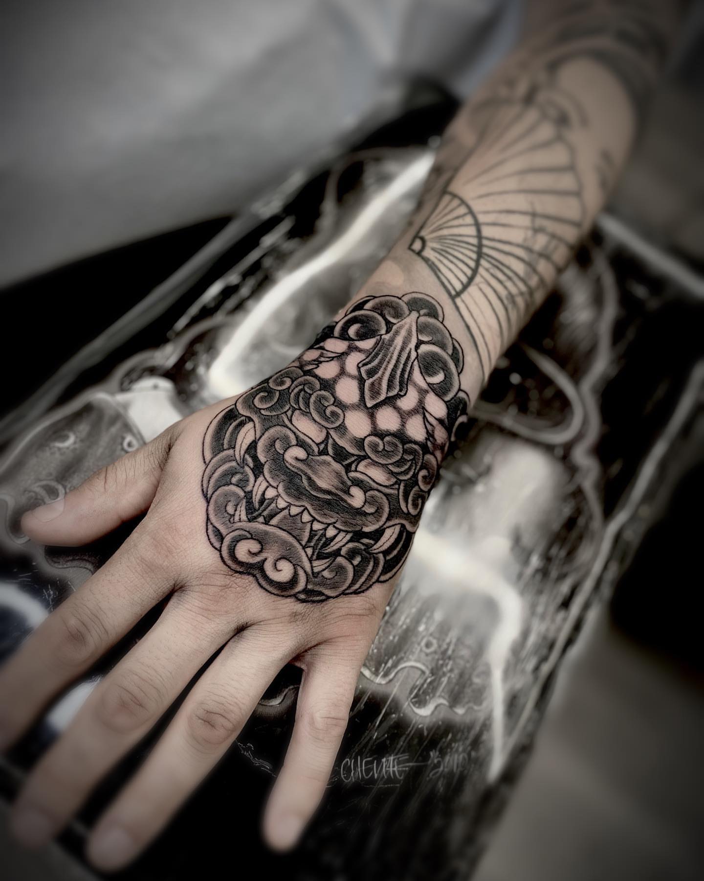 Cloud and wave black and grey tattoo on the hand by Daniel Gutierrez