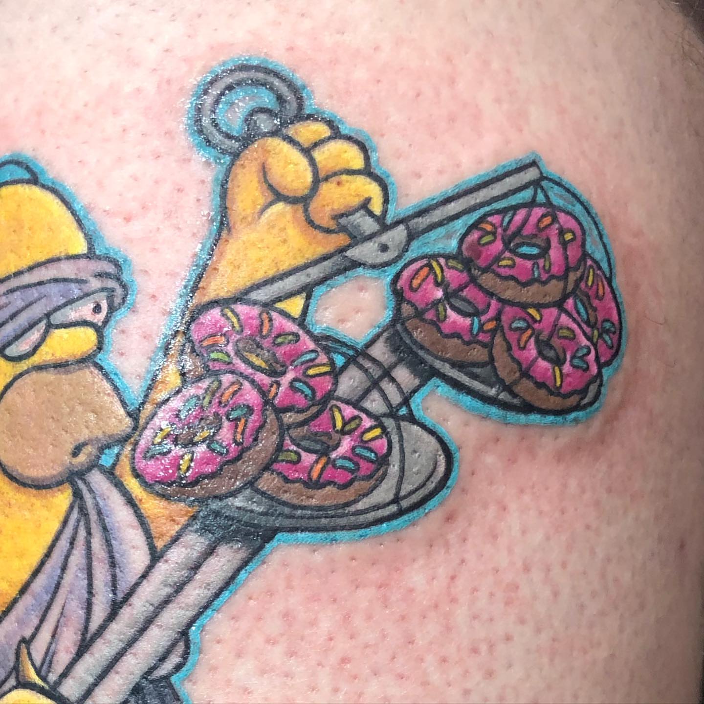 Donuts and Homer Simpson new school tattoo on the upper arm by Walter Frank