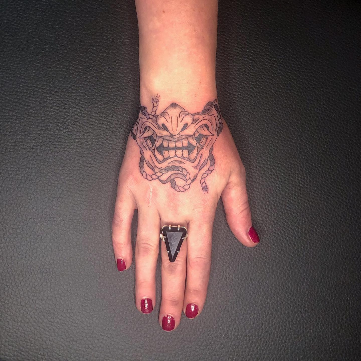 Demon mask black and grey tattoo on the hand by NYC