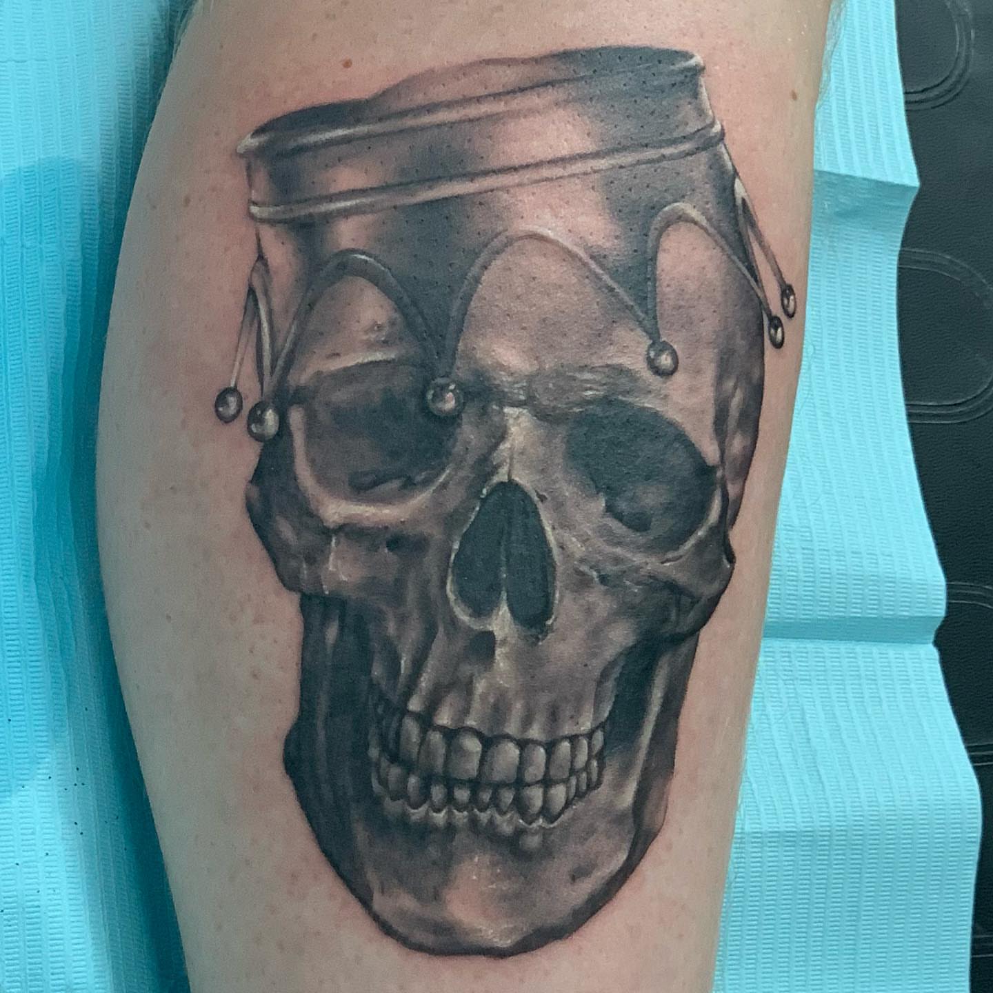 Skull with jester hat realism tattoo on the forearm by Trevor Sibary