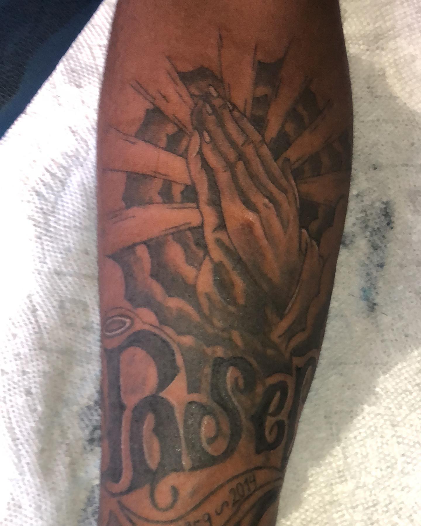 Praying hands black and grey tattoo on the forearm by Dre Inks