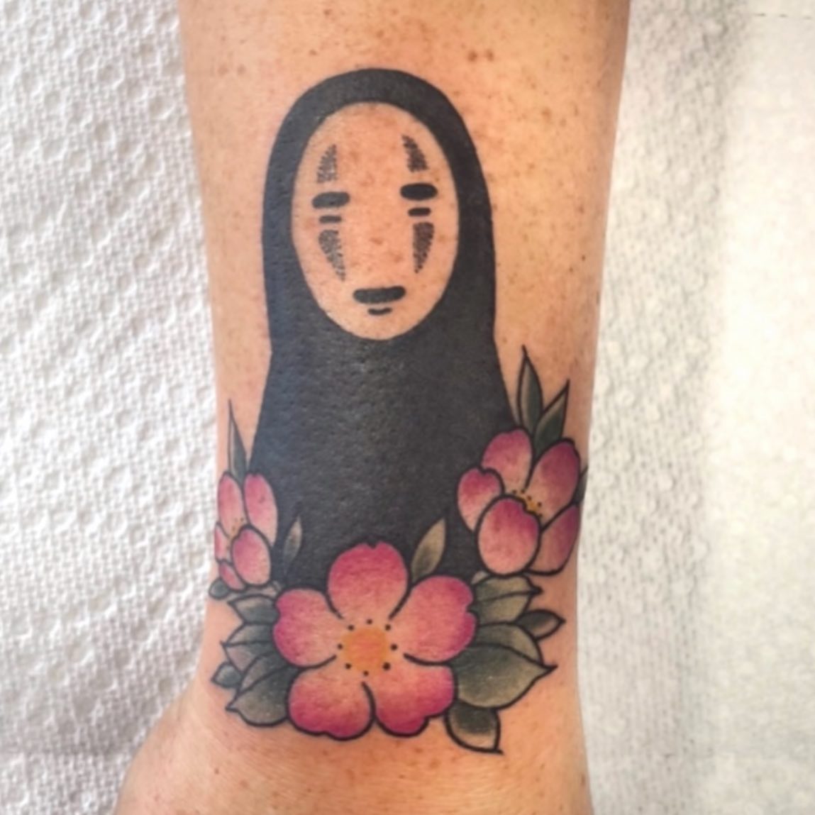 No face character with flowers anime tattoo on the forearm by Danielle Dubois