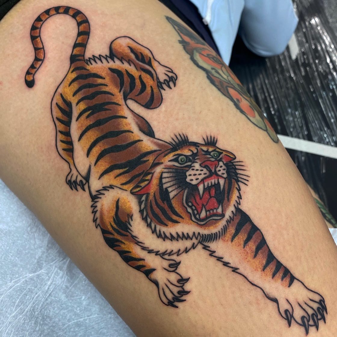 Roaring tiger American traditional tattoo on the thigh by Dave G