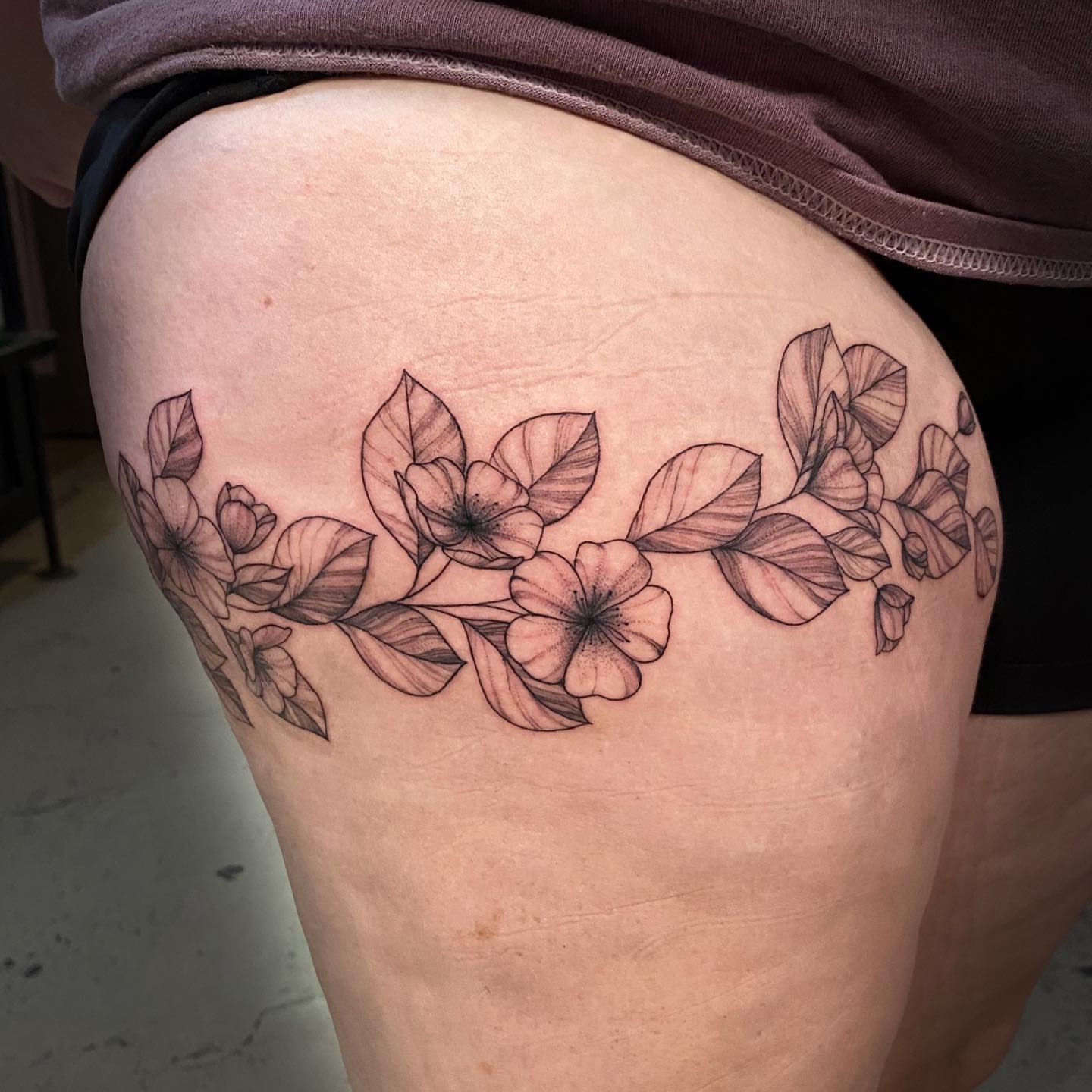 Flower vine black and grey tattoo on the thigh by Emily Conner