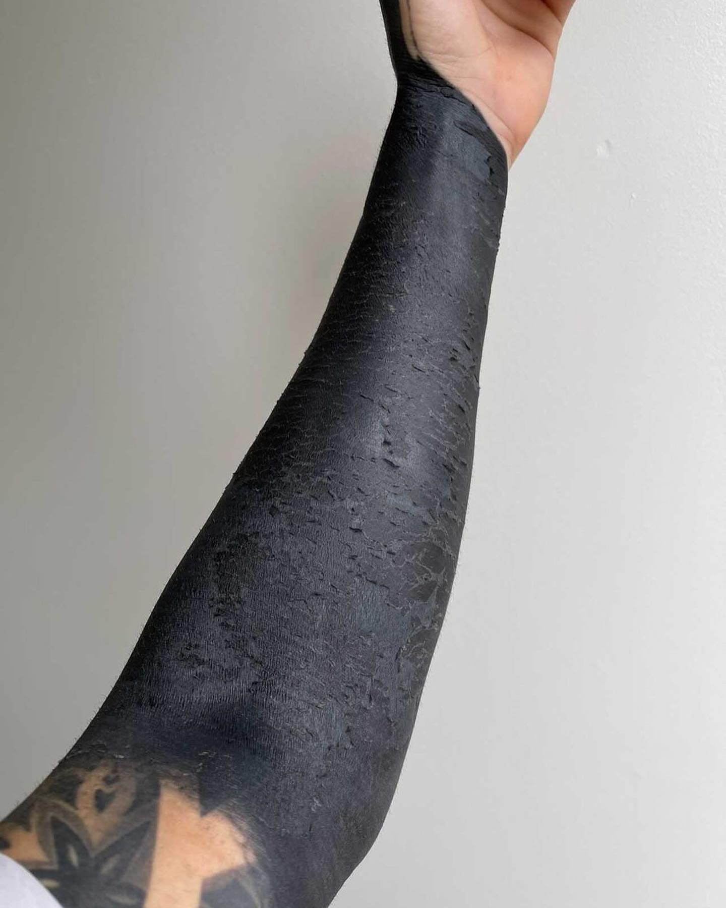 Blackout blackwork tattoo on the upper arm by Mark Walker