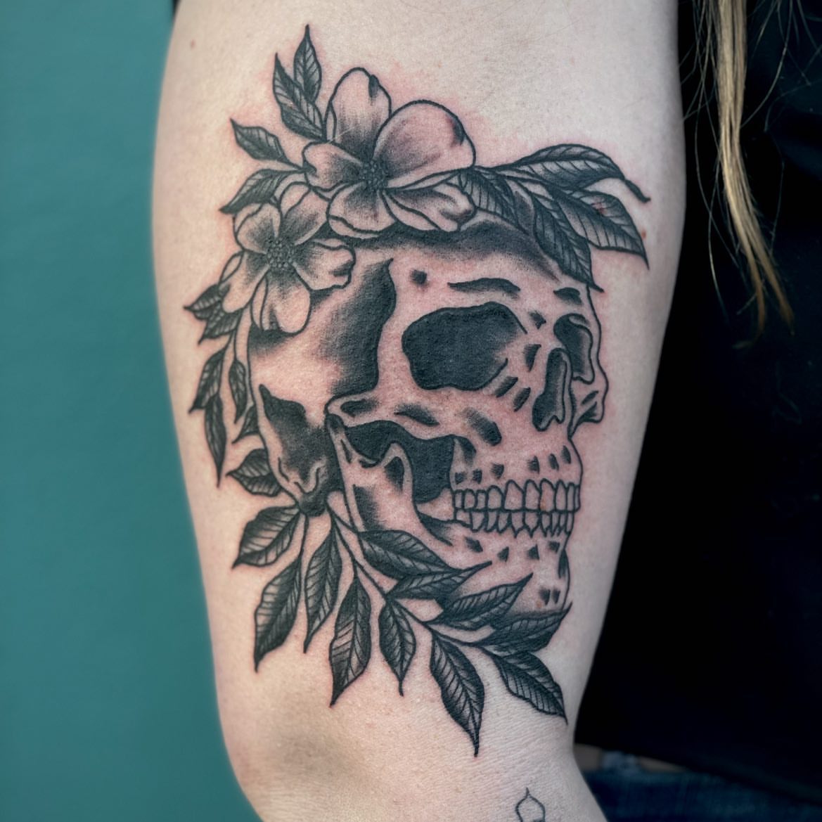 Skull with flowers realism tattoo on the forearm by Erin Stephens
