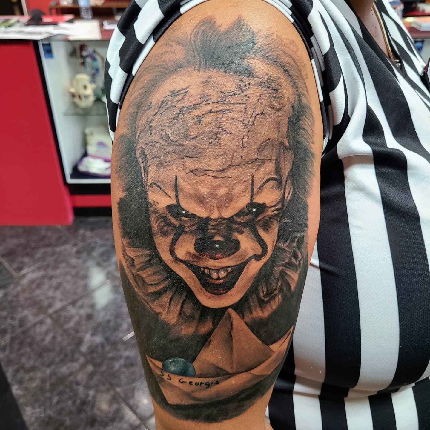 Pennywise the Clown realism tattoo on the upper arm by Dan Redding