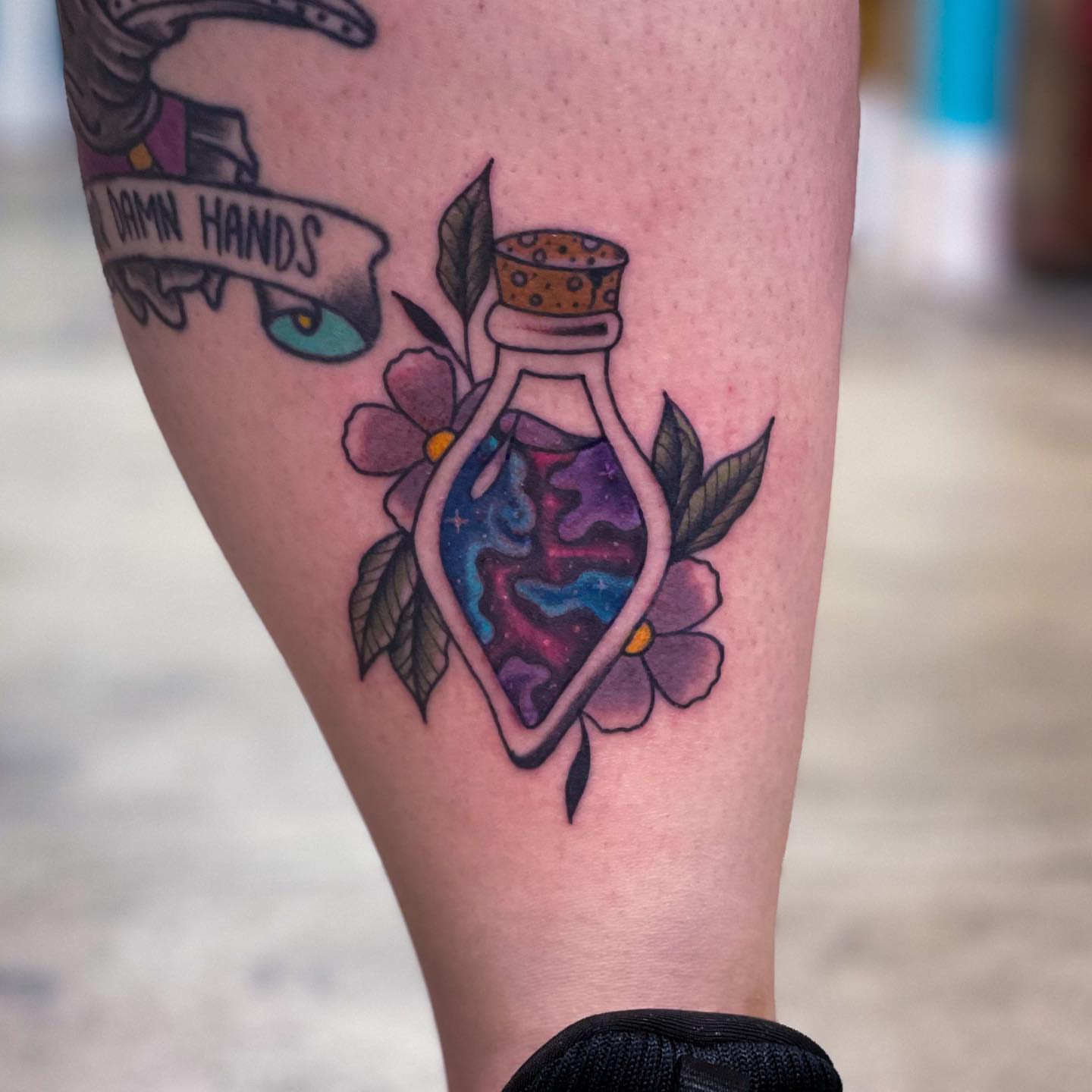 Glass bottle with cosmic scene American traditional tattoo on the forearm by Erin Stephens