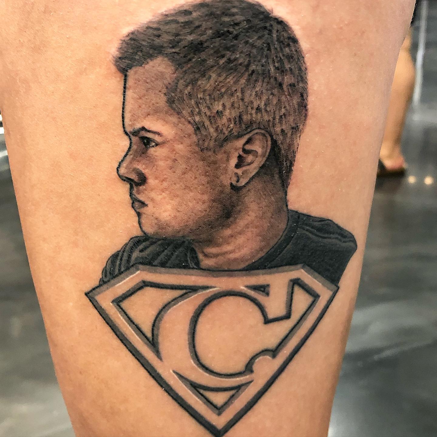 Boy and superman logo realism tattoo on the forearm by 𝕵𝖆𝖞 𝕽𝖎𝖟𝖟𝖔