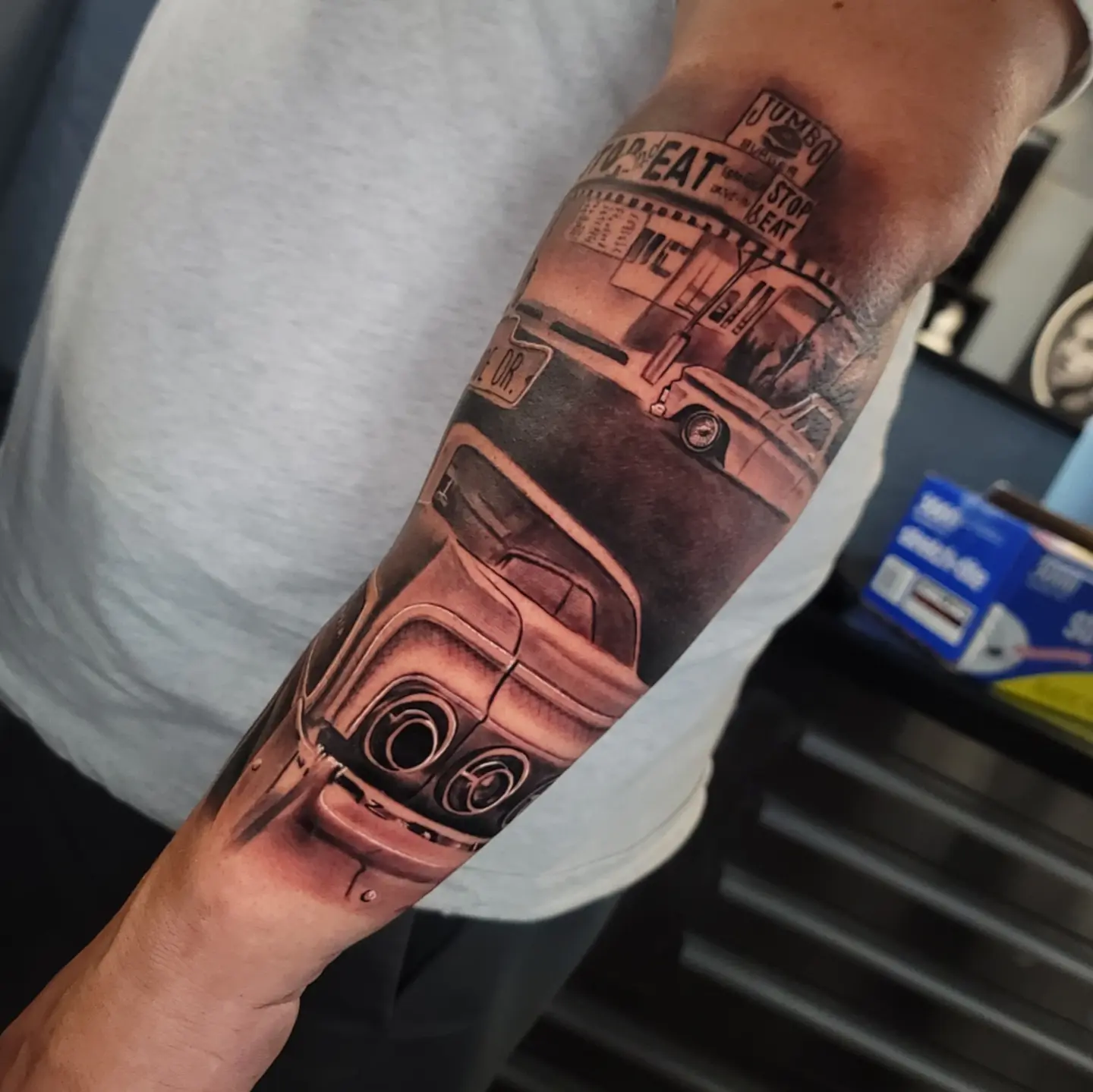 Diner scene realism tattoo on the forearm by Angel Lizarraga
