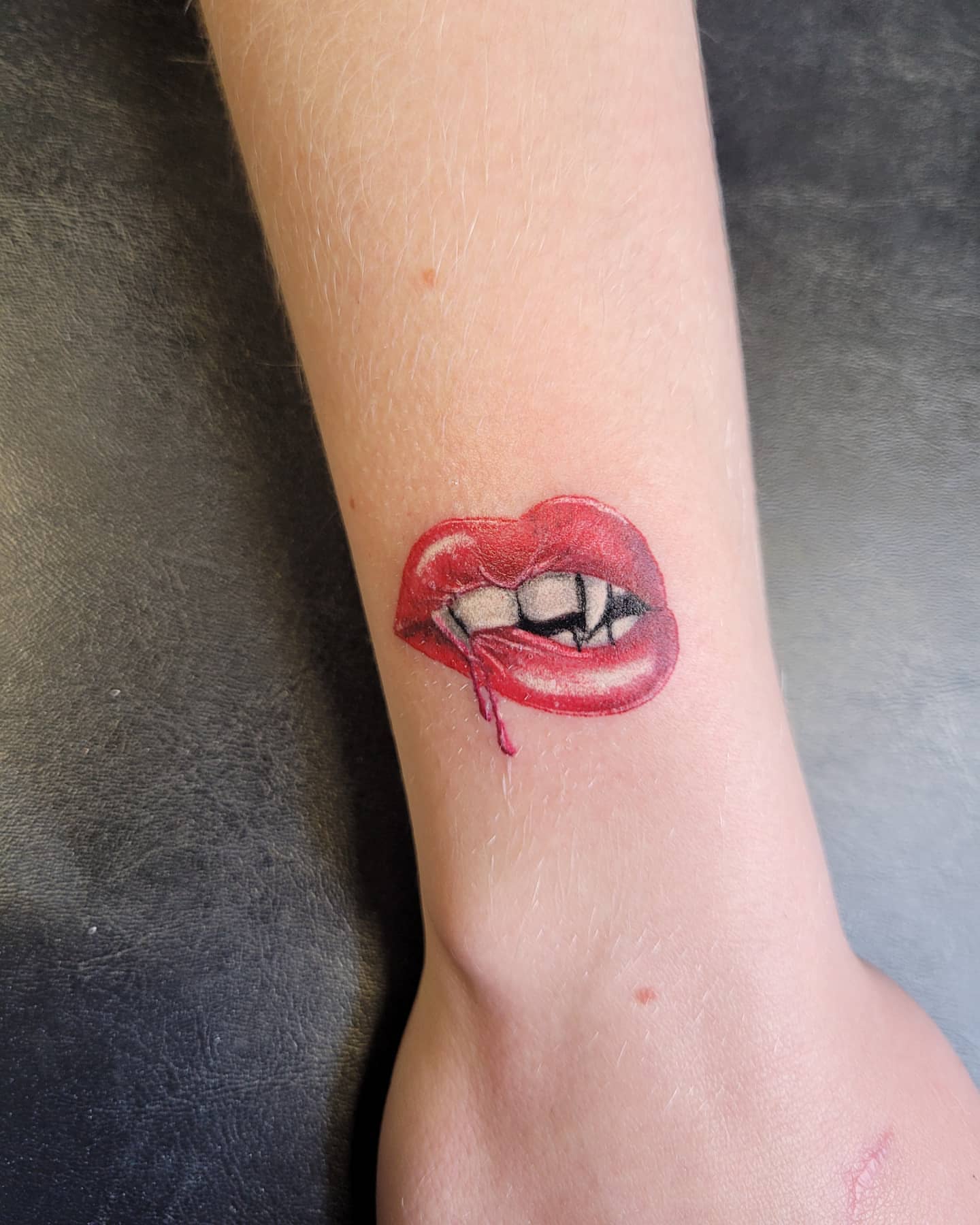 Red lips realism tattoo on the forearm by Glen Wallis