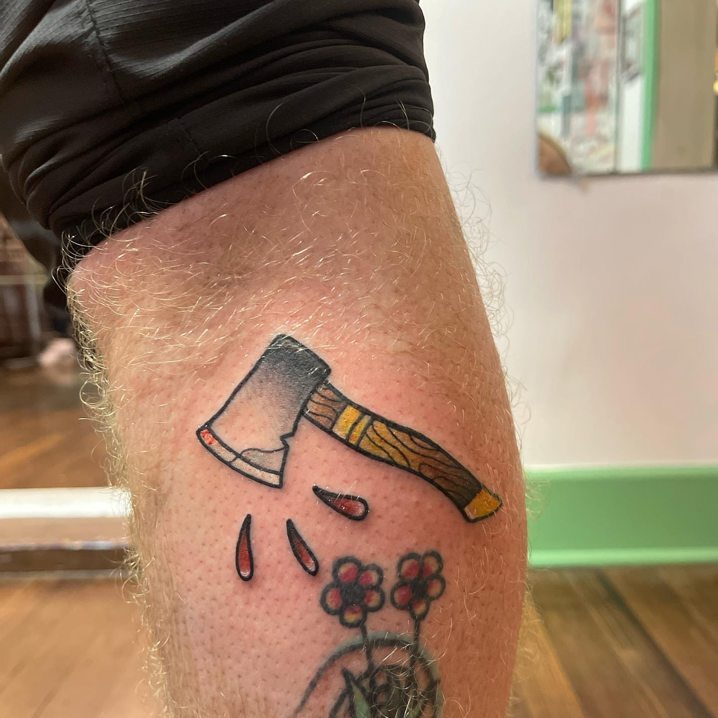 Axe and flowers dotwork tattoo on the thigh by Erin Miller