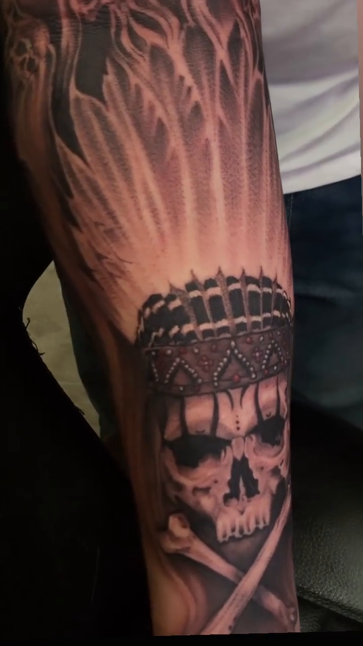 Skull with headdress and bones realism tattoo by @young_sely
