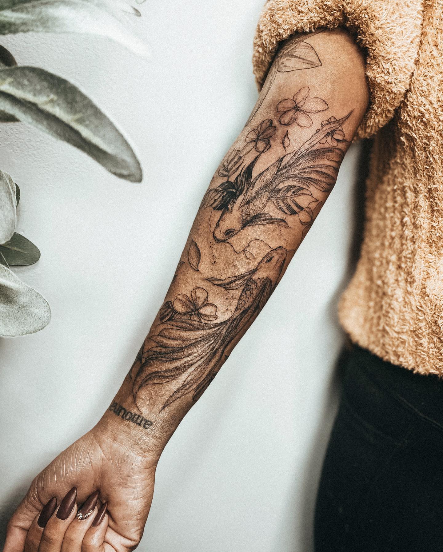 Fish and flowers black and grey tattoo on the forearm by Ayauna Mai