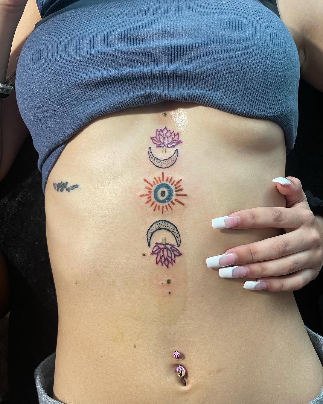 Sun, moon, and lotus flowers fine line tattoo on the torso by InkByChing❤️🔥