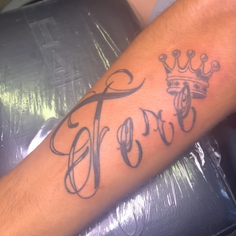 Name with crown lettering script tattoo on the forearm by Wichita Tattoo
