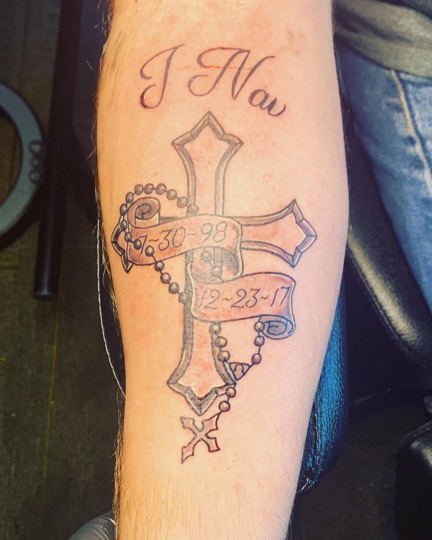Cross with rosary black and grey tattoo on the forearm by Wichita Tattoo
