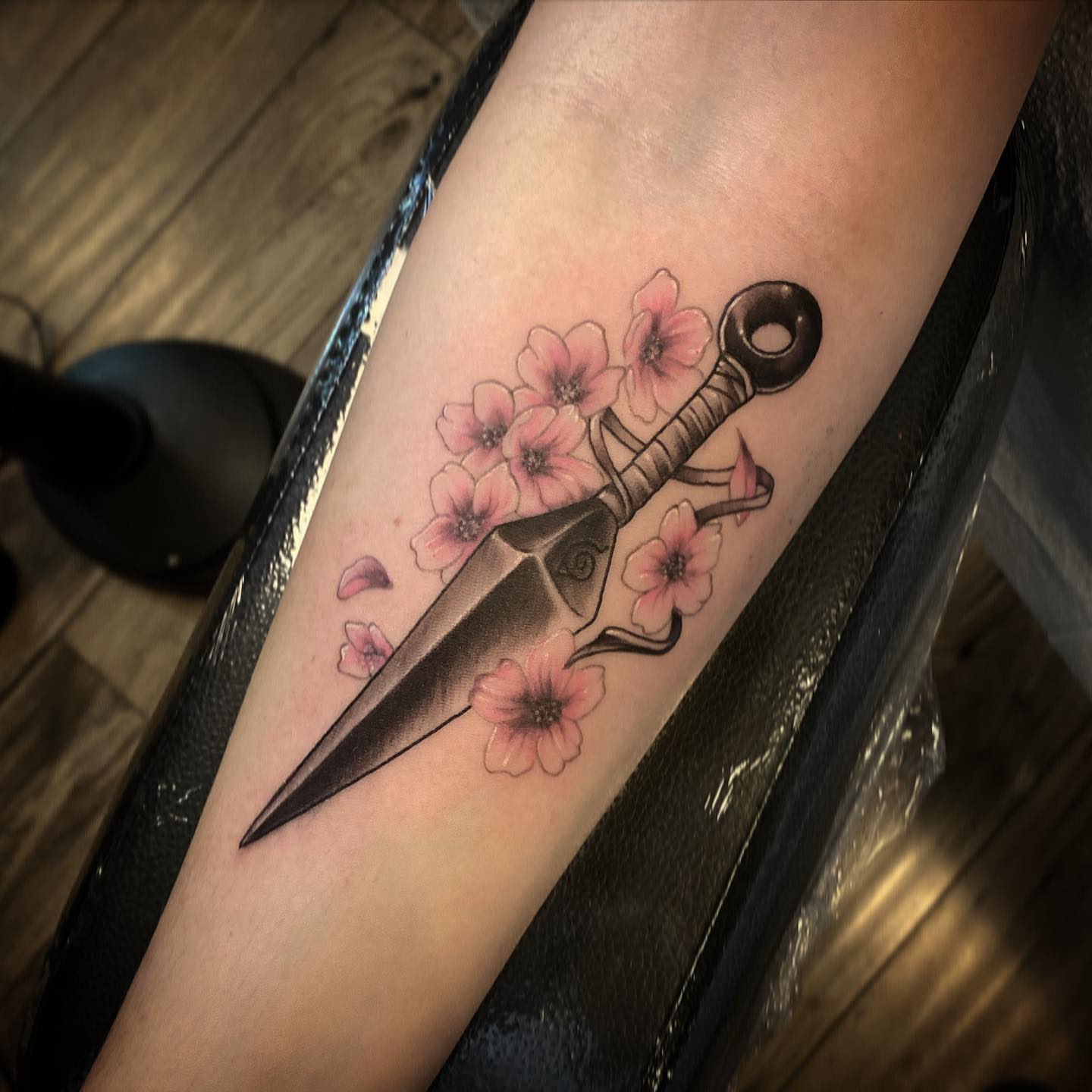Cherry blossoms and dagger neo-traditional tattoo on the forearm by ⠀⠀ ⠀ ⠀ ⠀⠀ ⠀⠀ ⠀⠀ ⠀ ⠀⠀ ⠀⠀ᎪᎳᏃ, West Hollywood, California