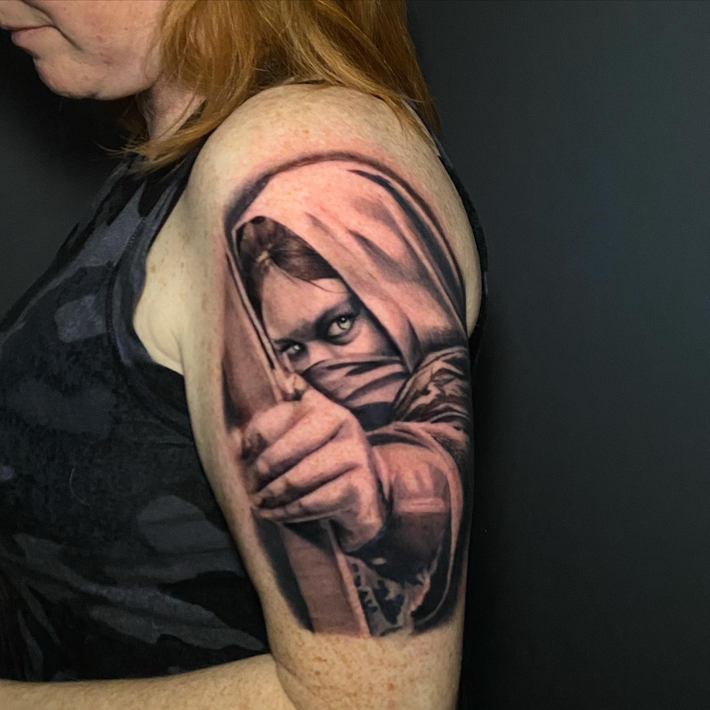 Mask-wearing figure realism tattoo on the shoulder by Lindsey Lane, Dallas, Texas
