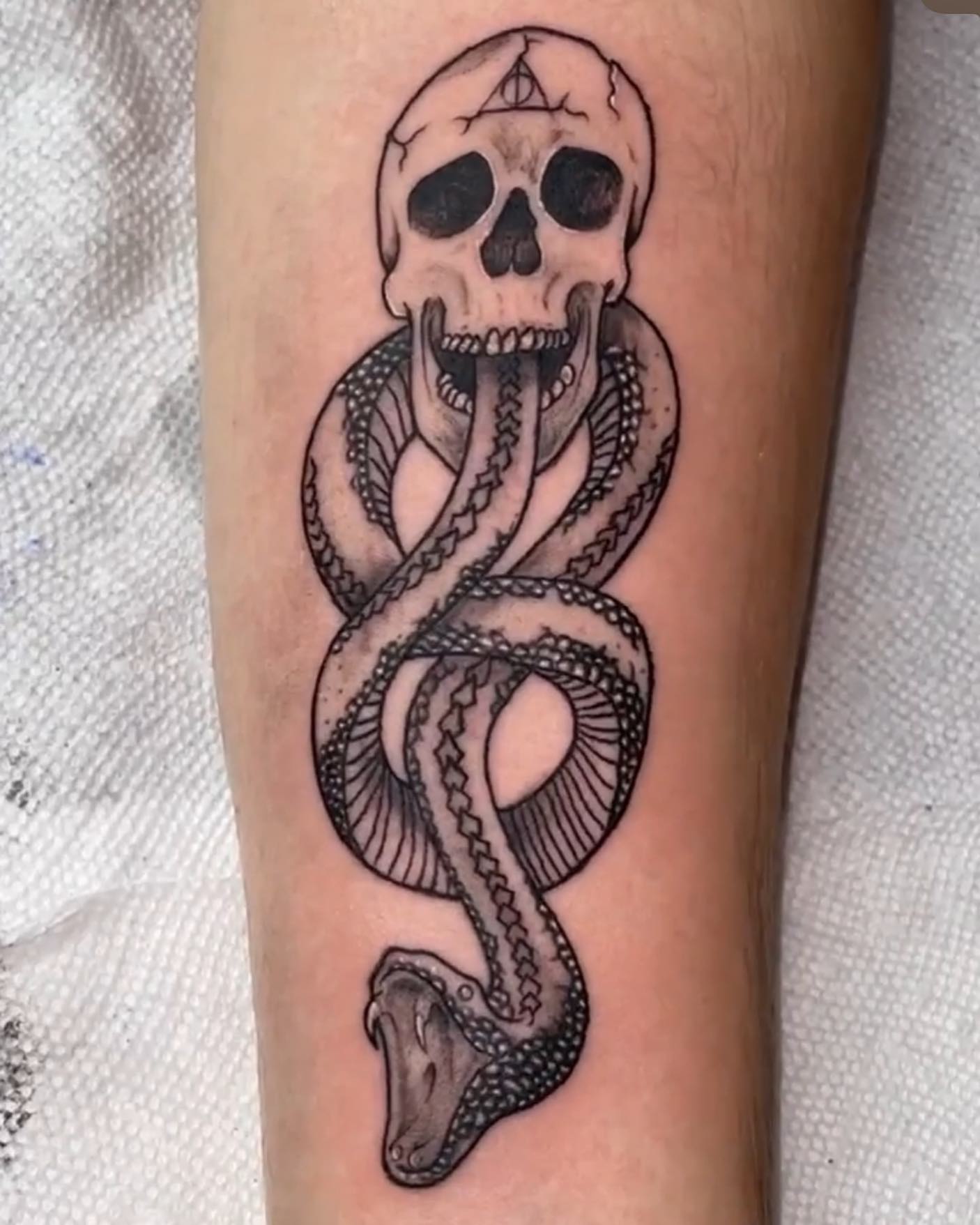 Snake and skull black and grey tattoo on the forearm by Christhian King