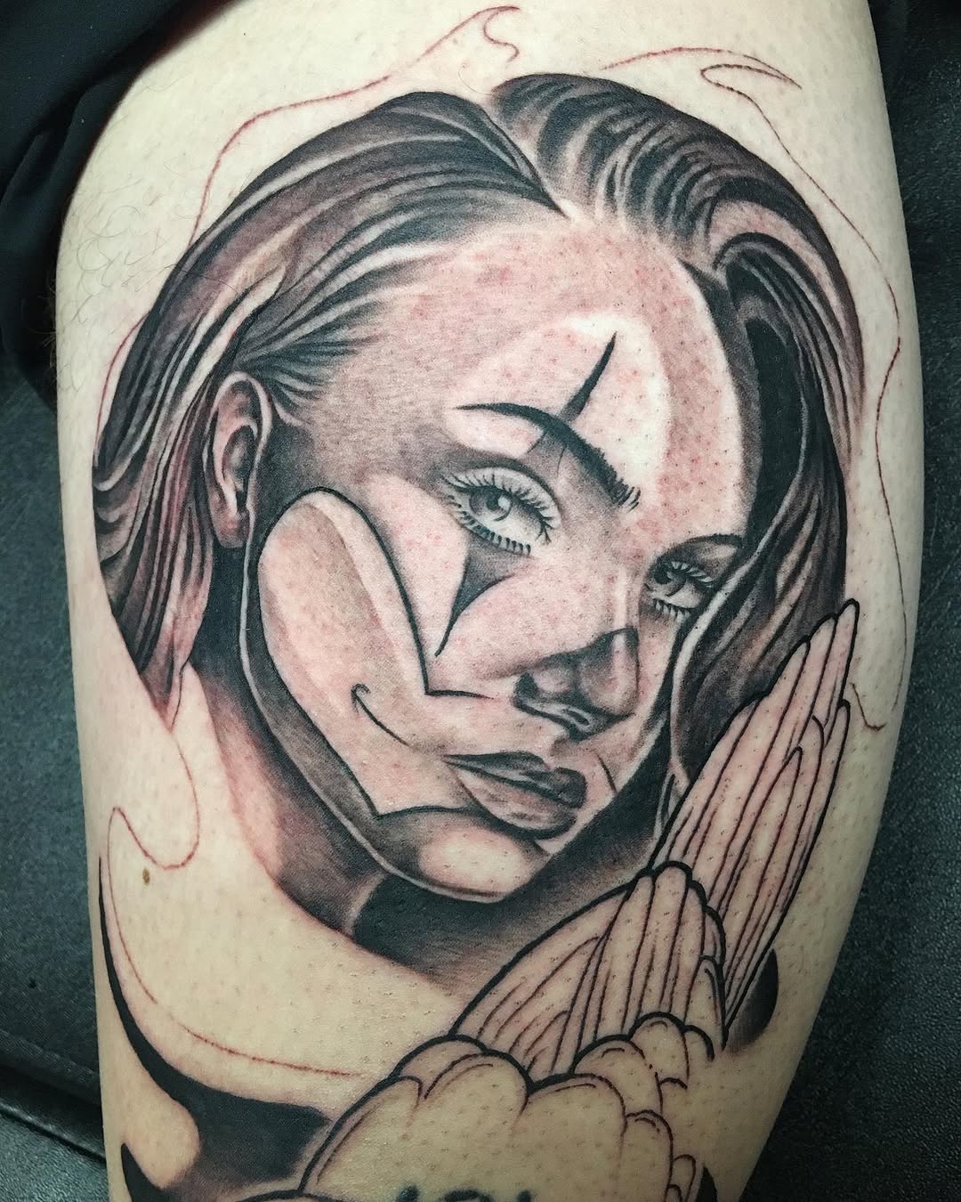 Woman with clown makeup and wings realism tattoo on the thigh by Cody Wolfe
