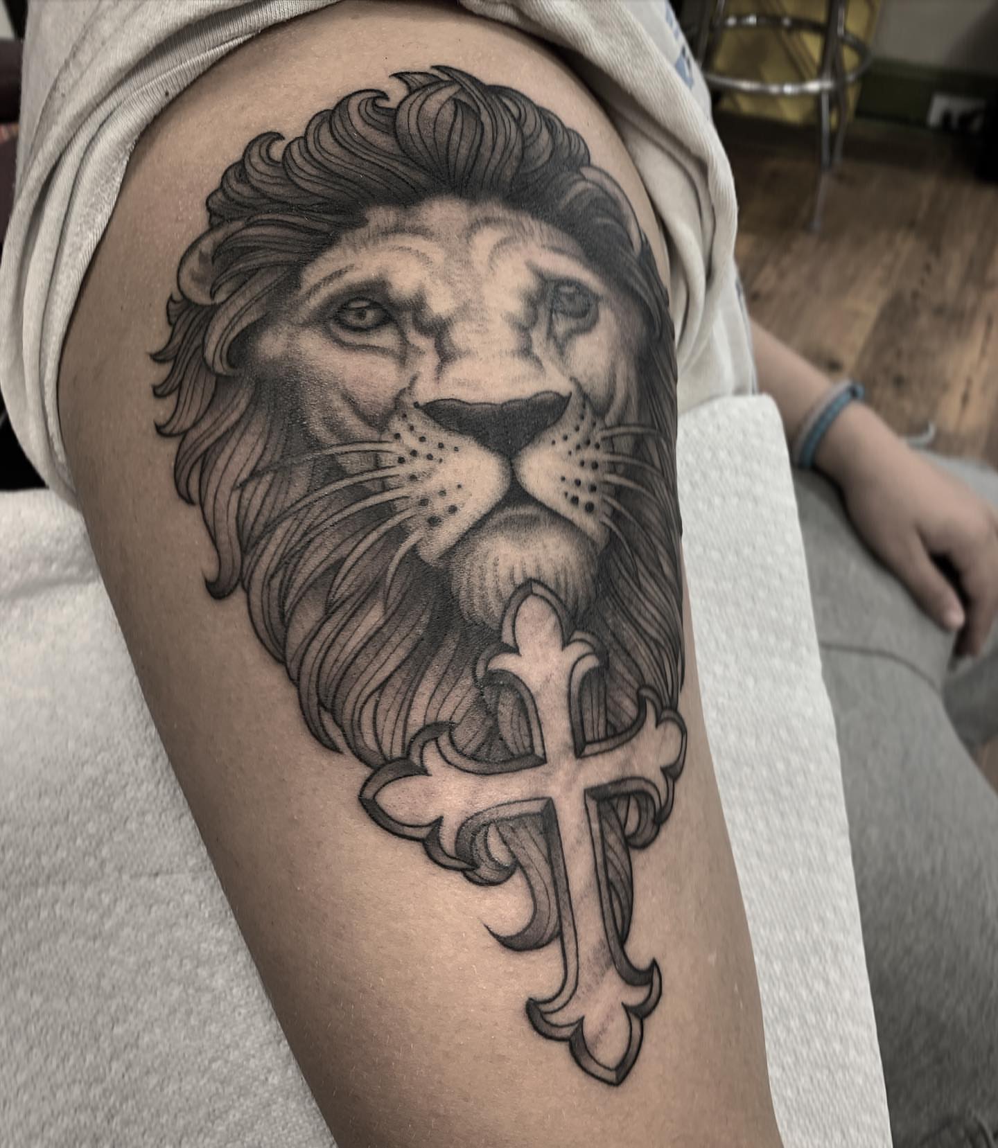 Lion and cross realism tattoo on the thigh by Pat Moser