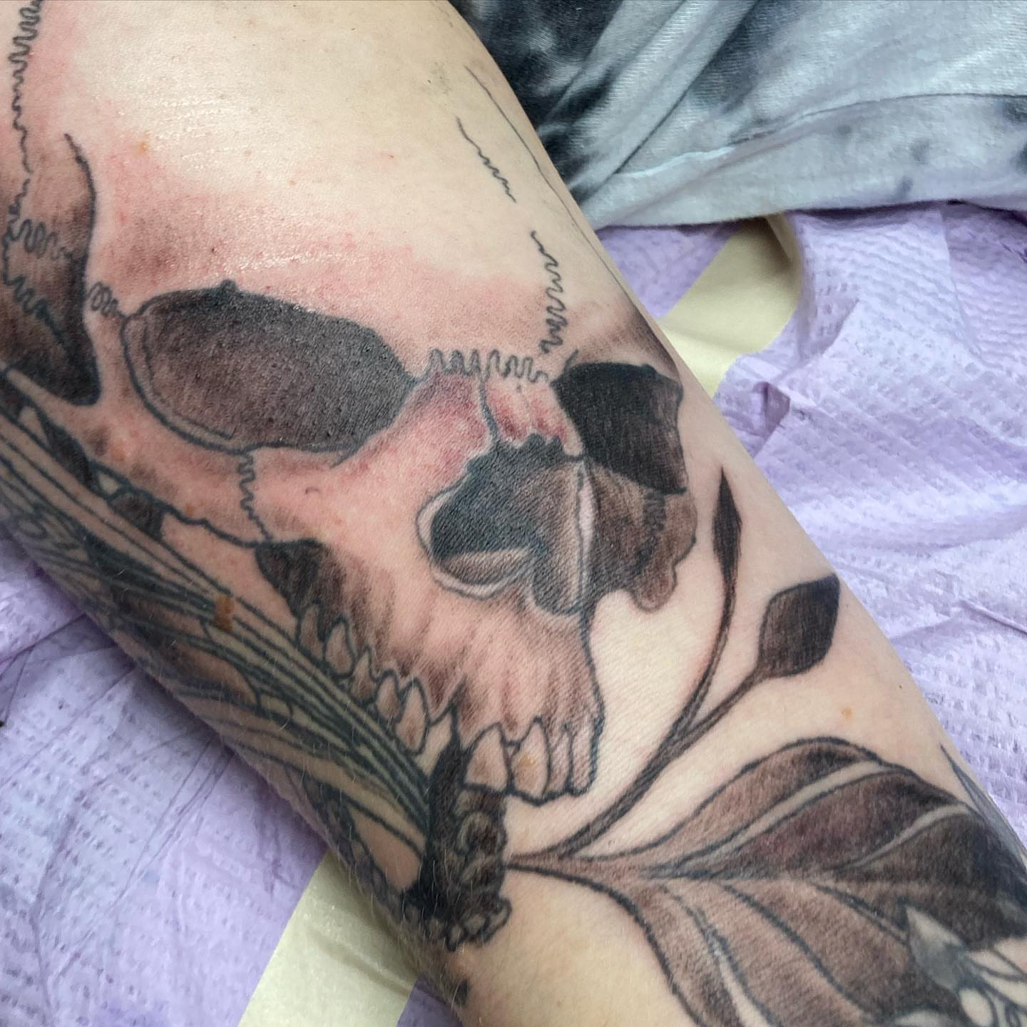 Skull and poppy black and grey tattoo on the forearm by Chuck House