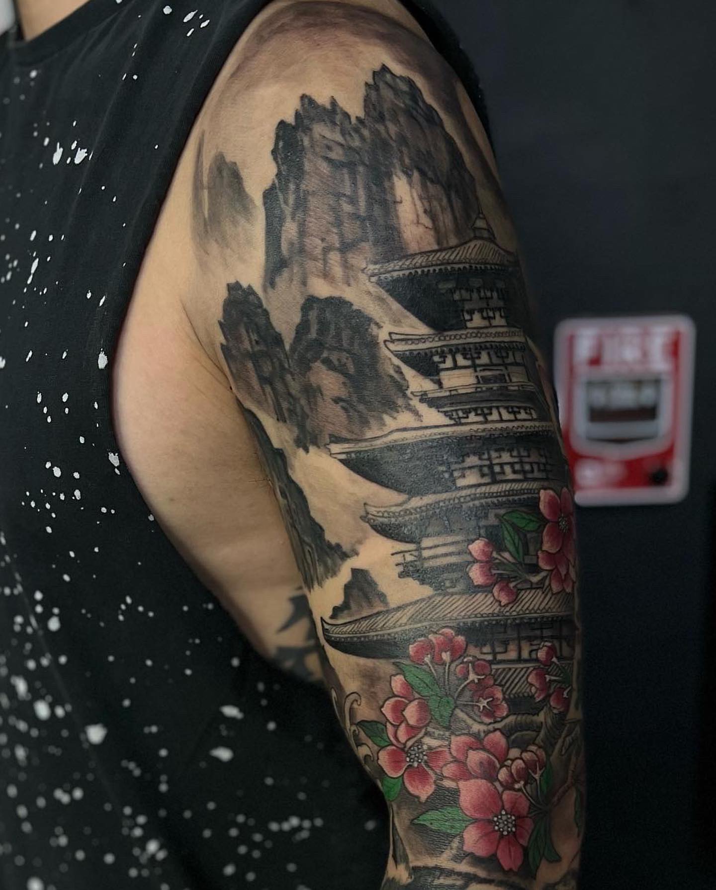 Mountain temple and cherry blossoms realism tattoo on the upper arm by Vinny Holistic Ink