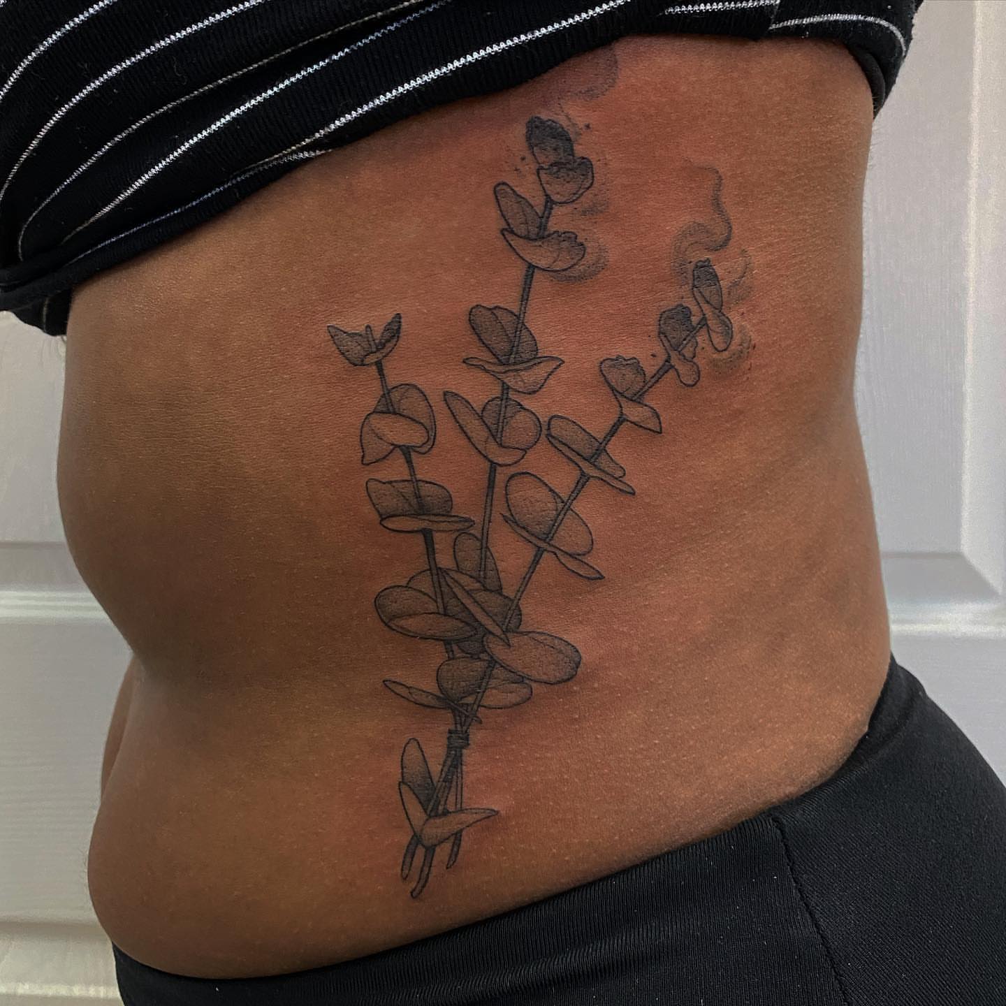 Eucalyptus branch black and grey tattoo on the torso by Marissa Tattoos