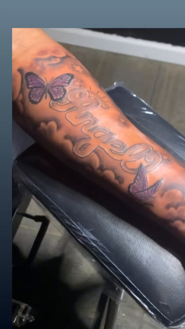 Name tattoo with butterflies and clouds lettering tattoo on the forearm by Wichita Tattoo