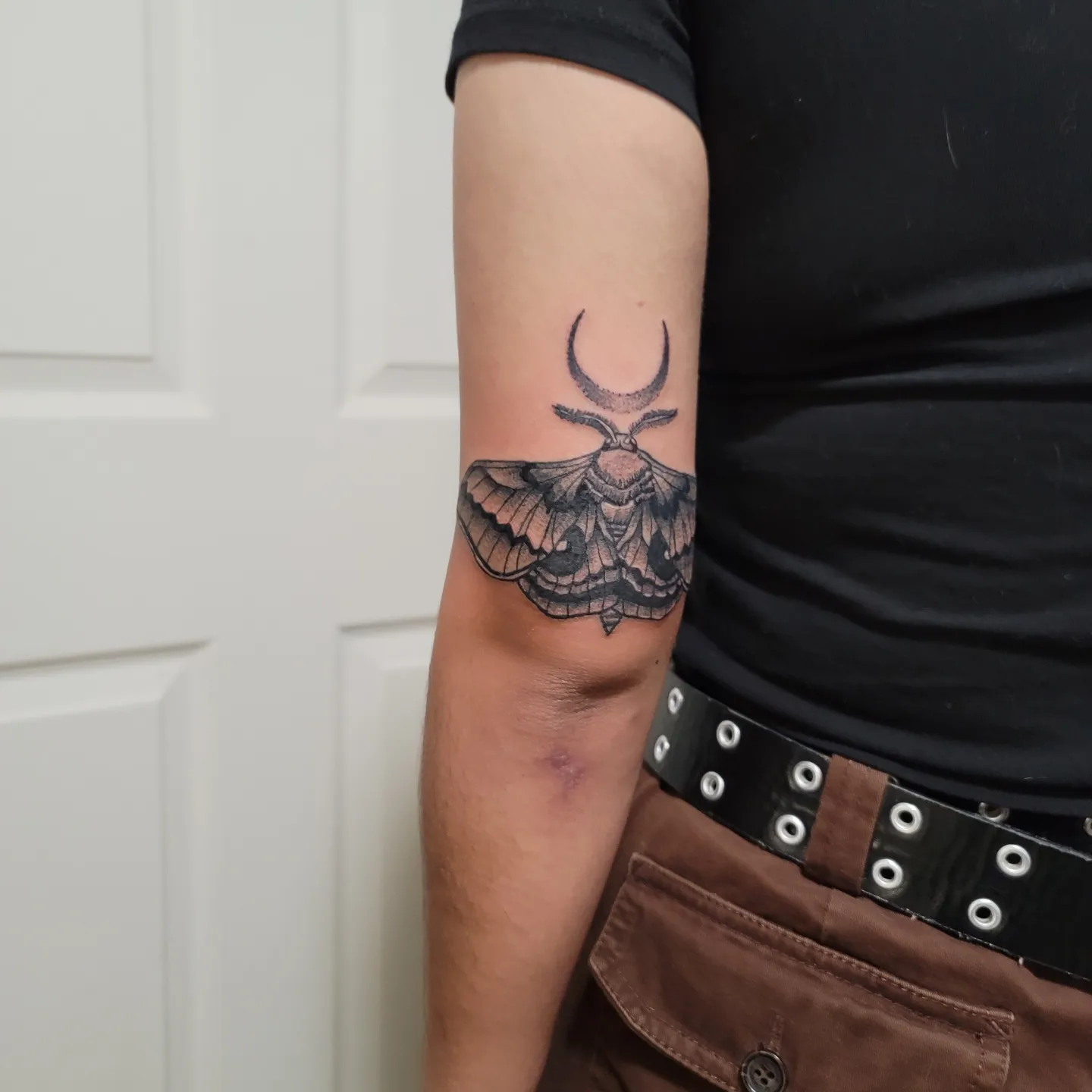 Moth with crescent moon black and grey tattoo on the forearm by Eddy
