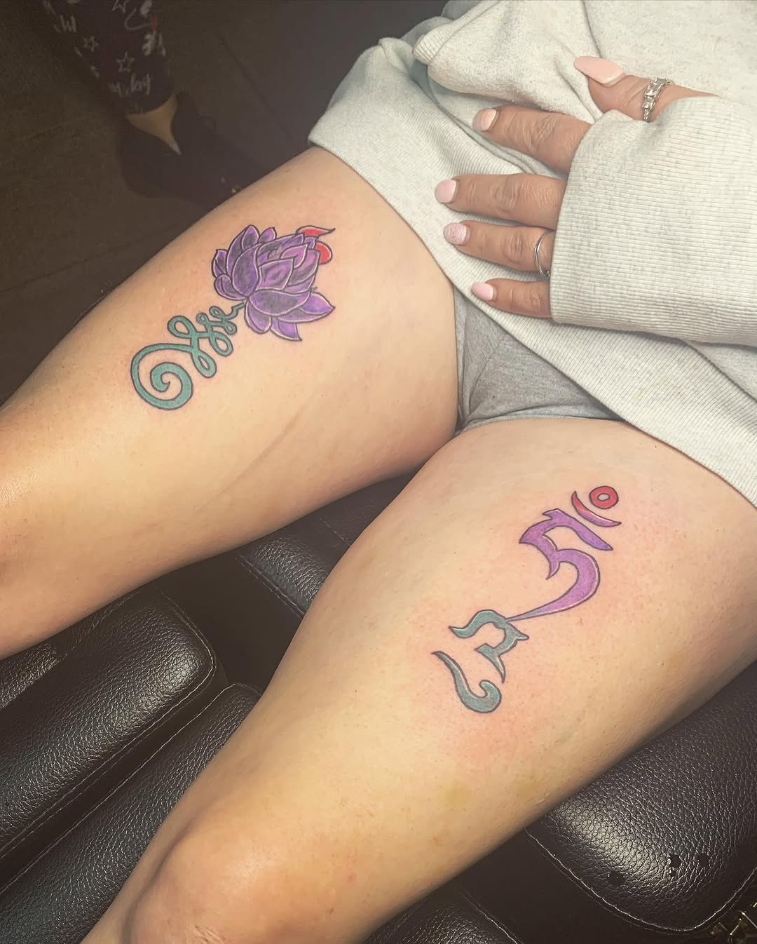 Lotus flower and sanskrit symbol fine line tattoo on the thigh by Wichita Tattoo