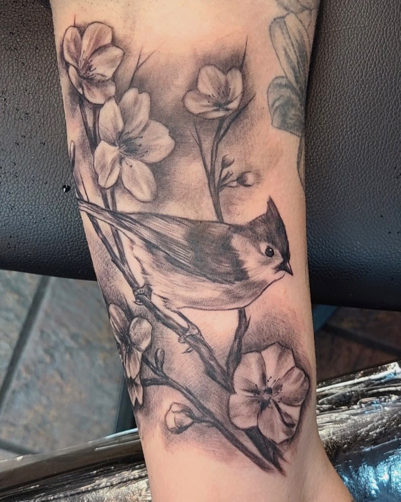 Bird and blossoms realism tattoo on the forearm by Comfy Chris Fettig