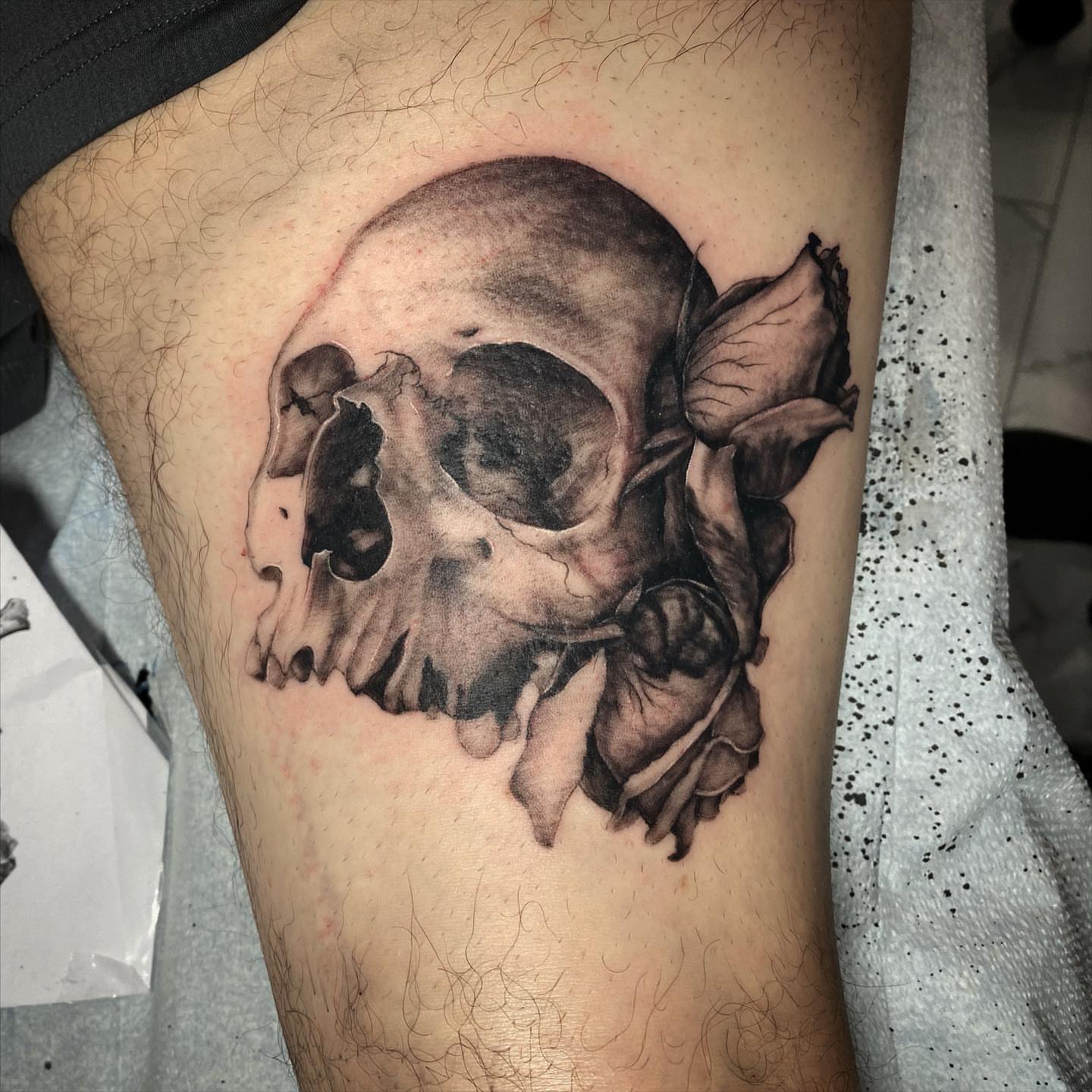 Skull and flower realism tattoo on the thigh by Mia