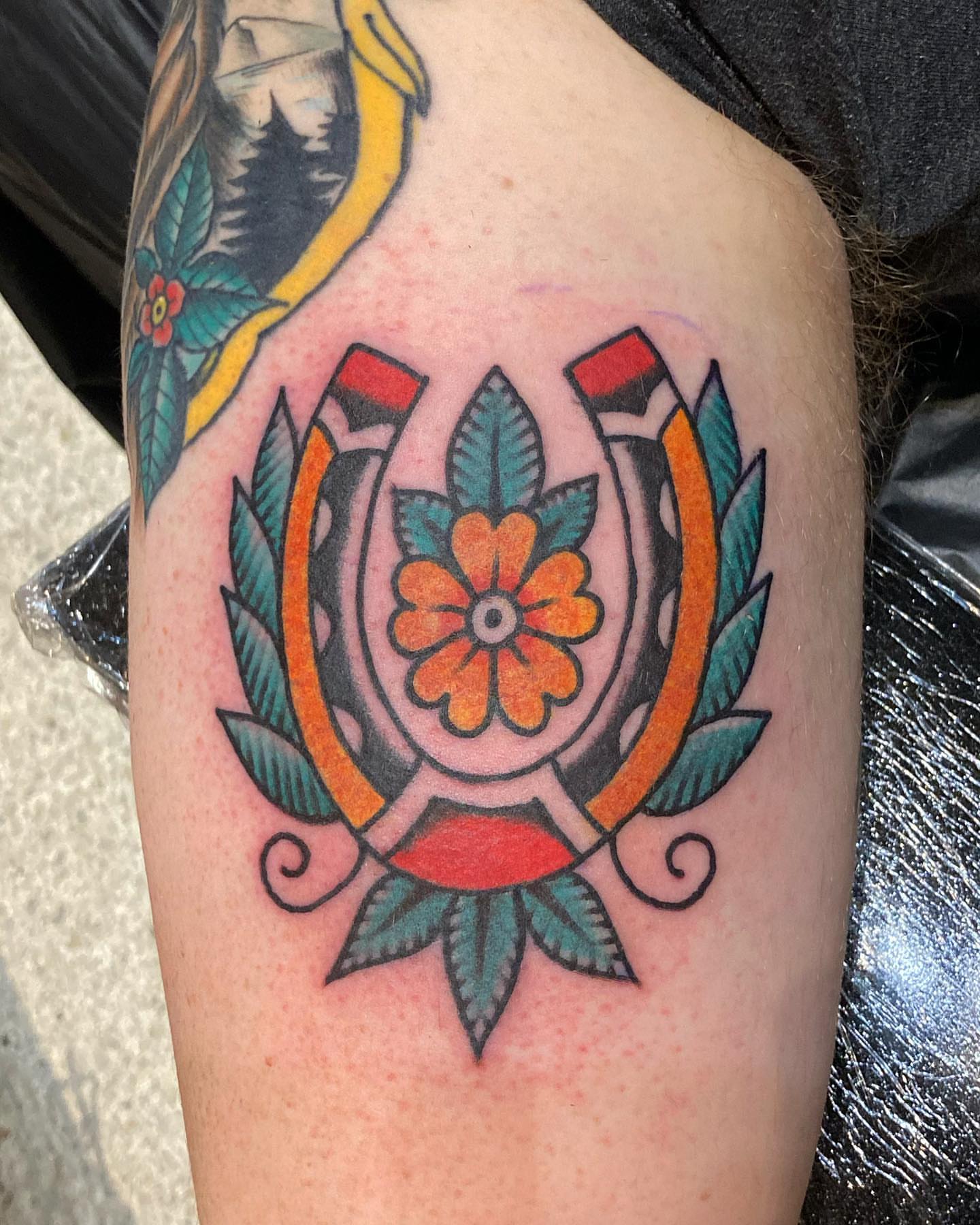 Horseshoe and flower American traditional tattoo on the upper arm by Rob Banks