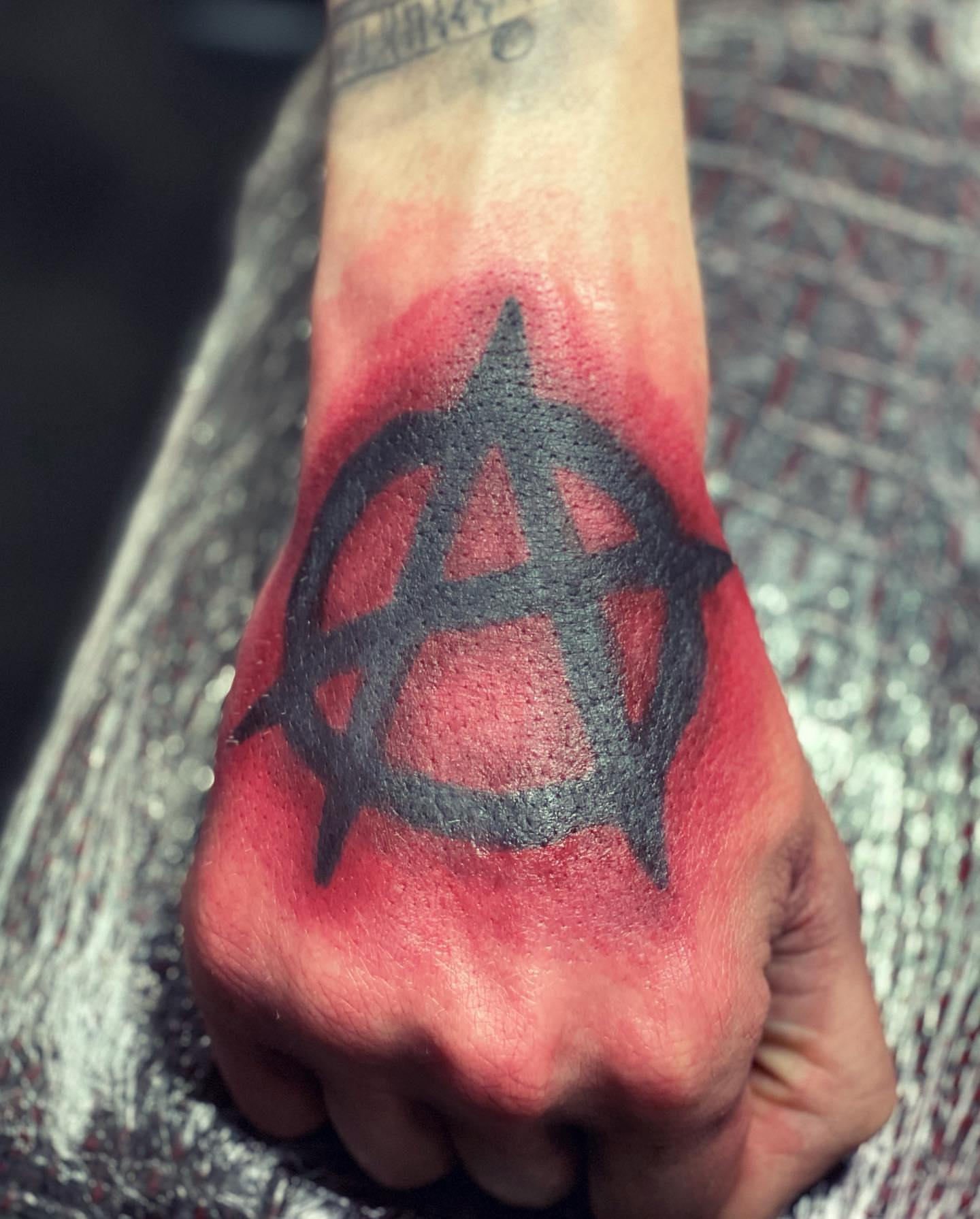 Anarchy symbol black and grey tattoo on the hand by Peewee Morales
