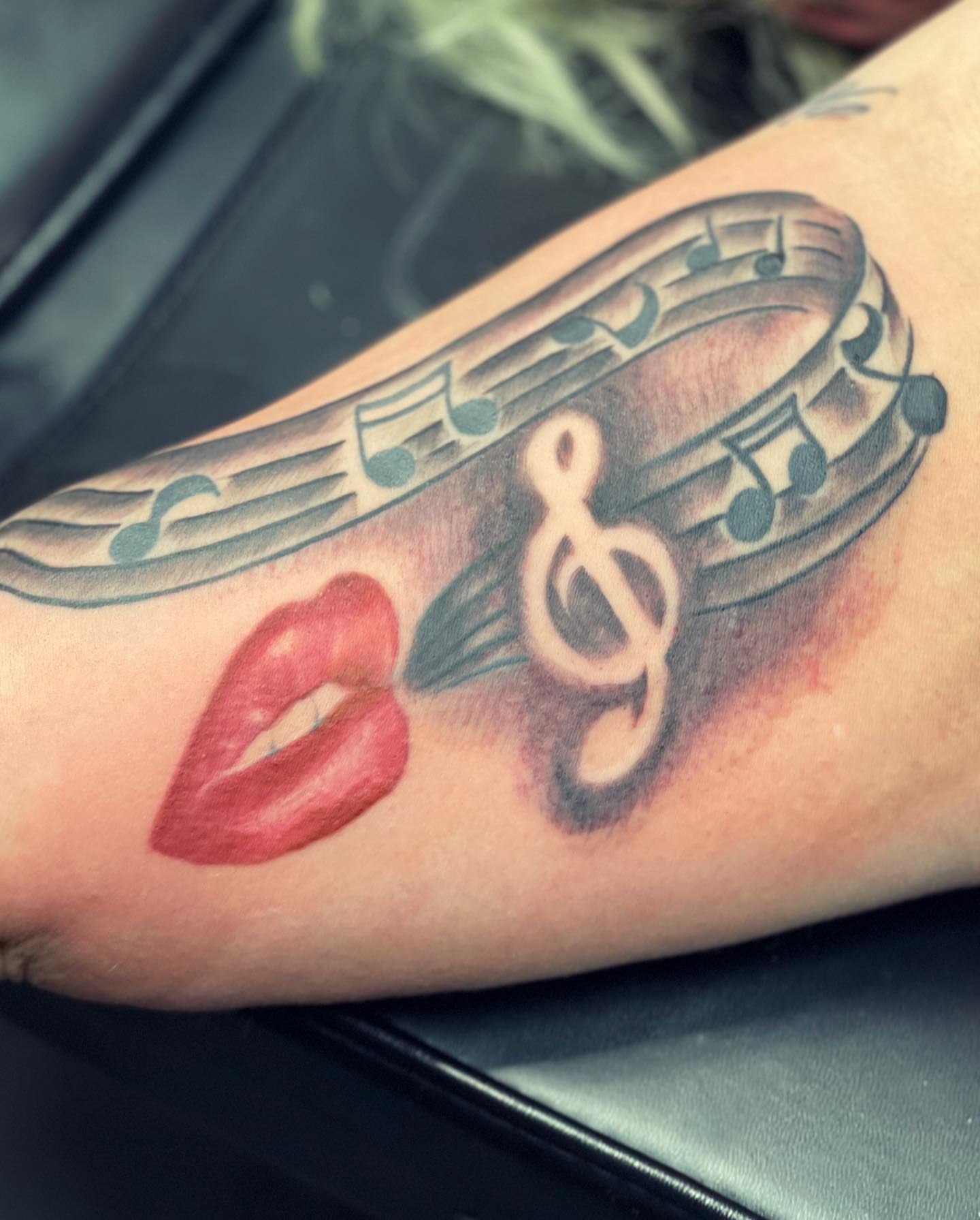 Lips and music notes black and grey tattoo on the forearm by Peewee Morales