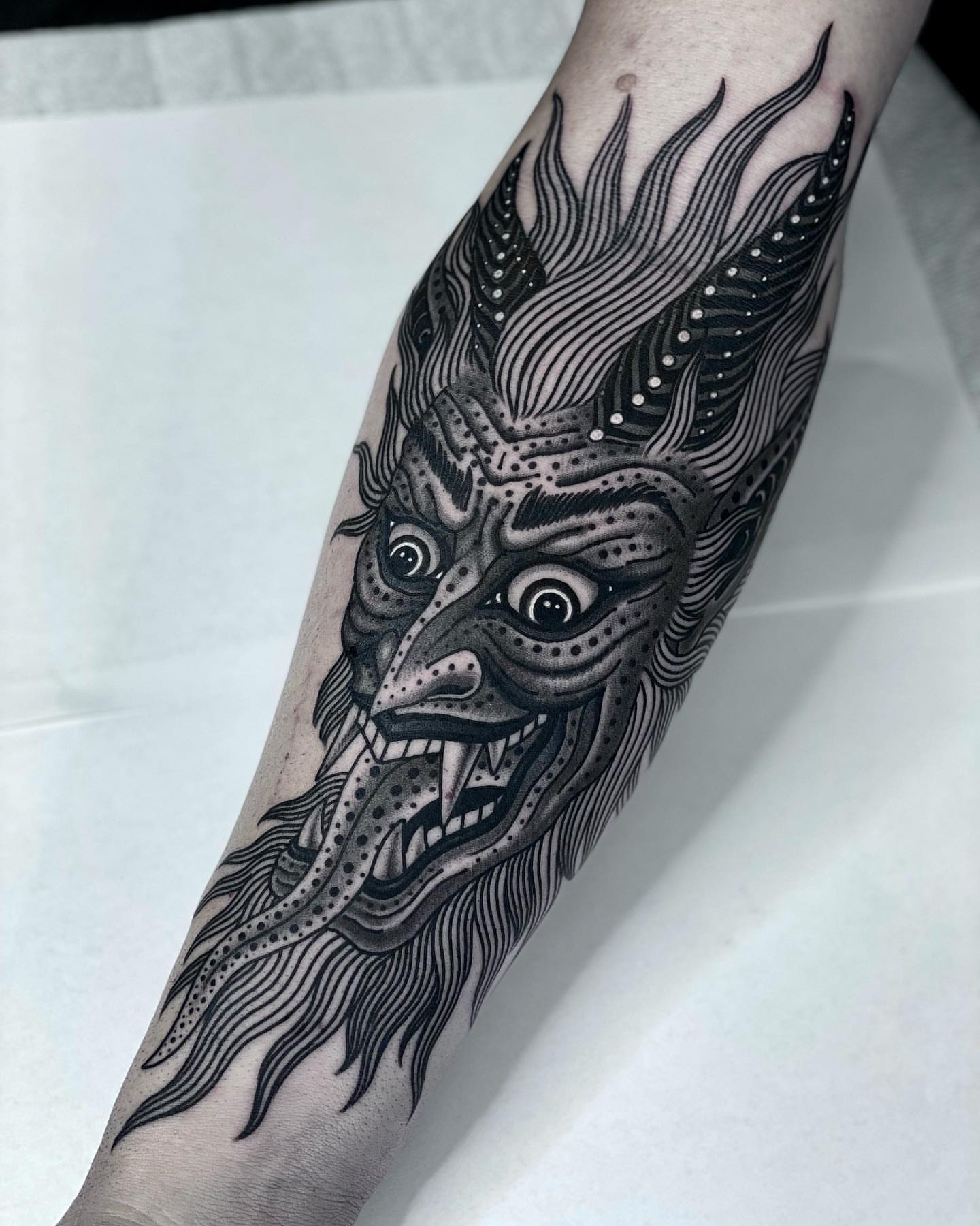 Demon mask dotwork tattoo on the forearm by Tyler Charles