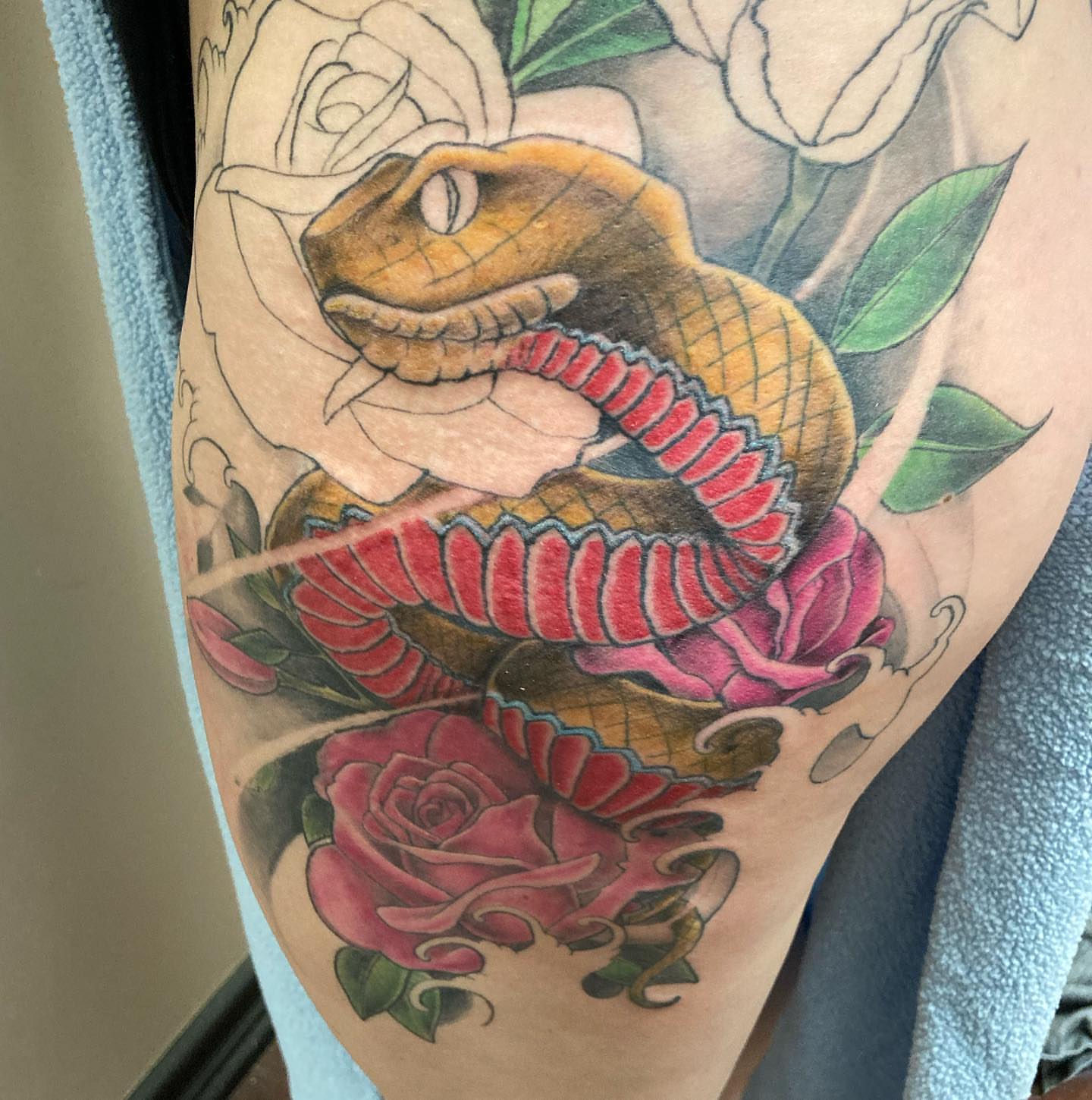Snake and roses American traditional tattoo on the forearm by Chuck House