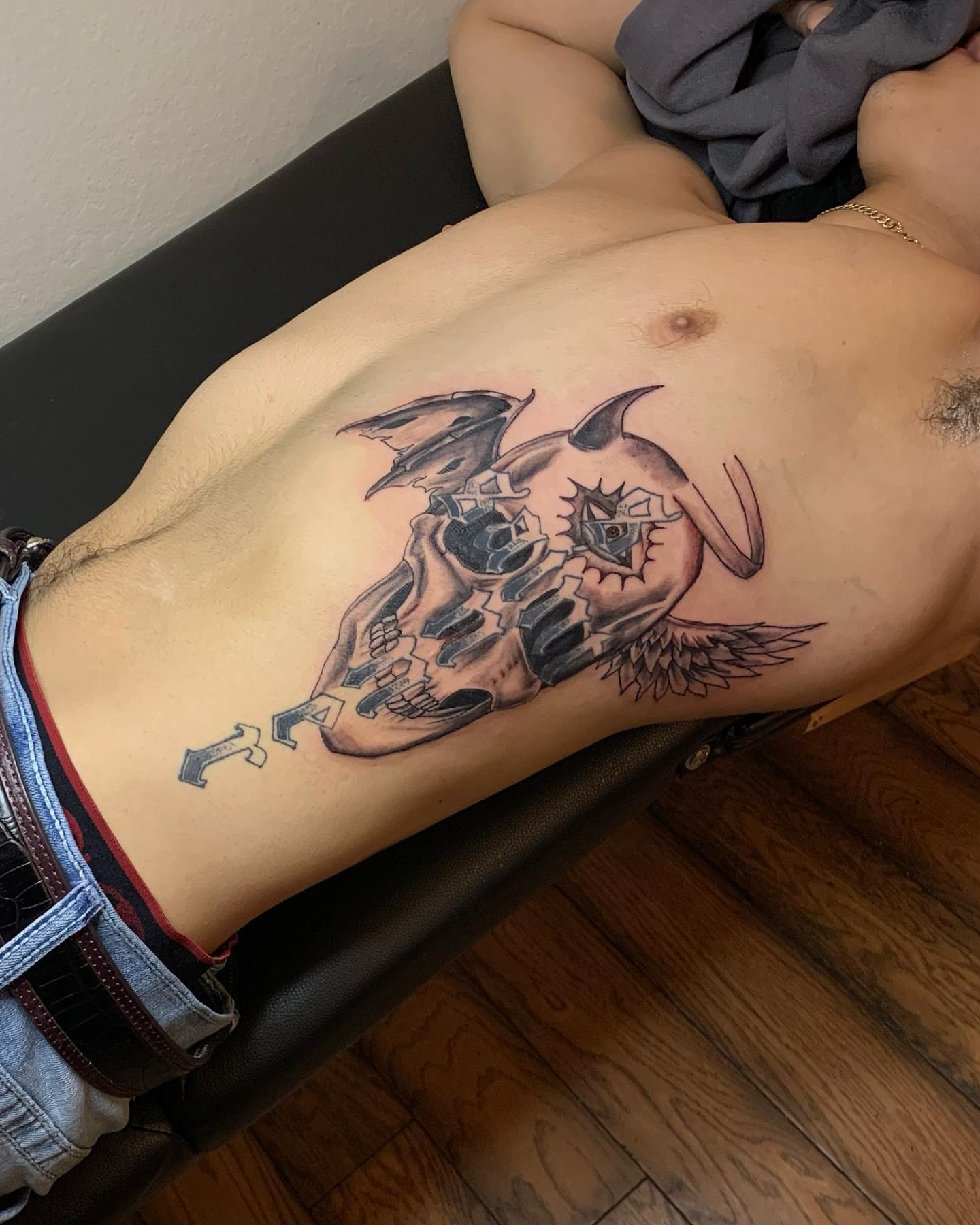 Skull with wings black and grey tattoo on the ribs by Leo Torres