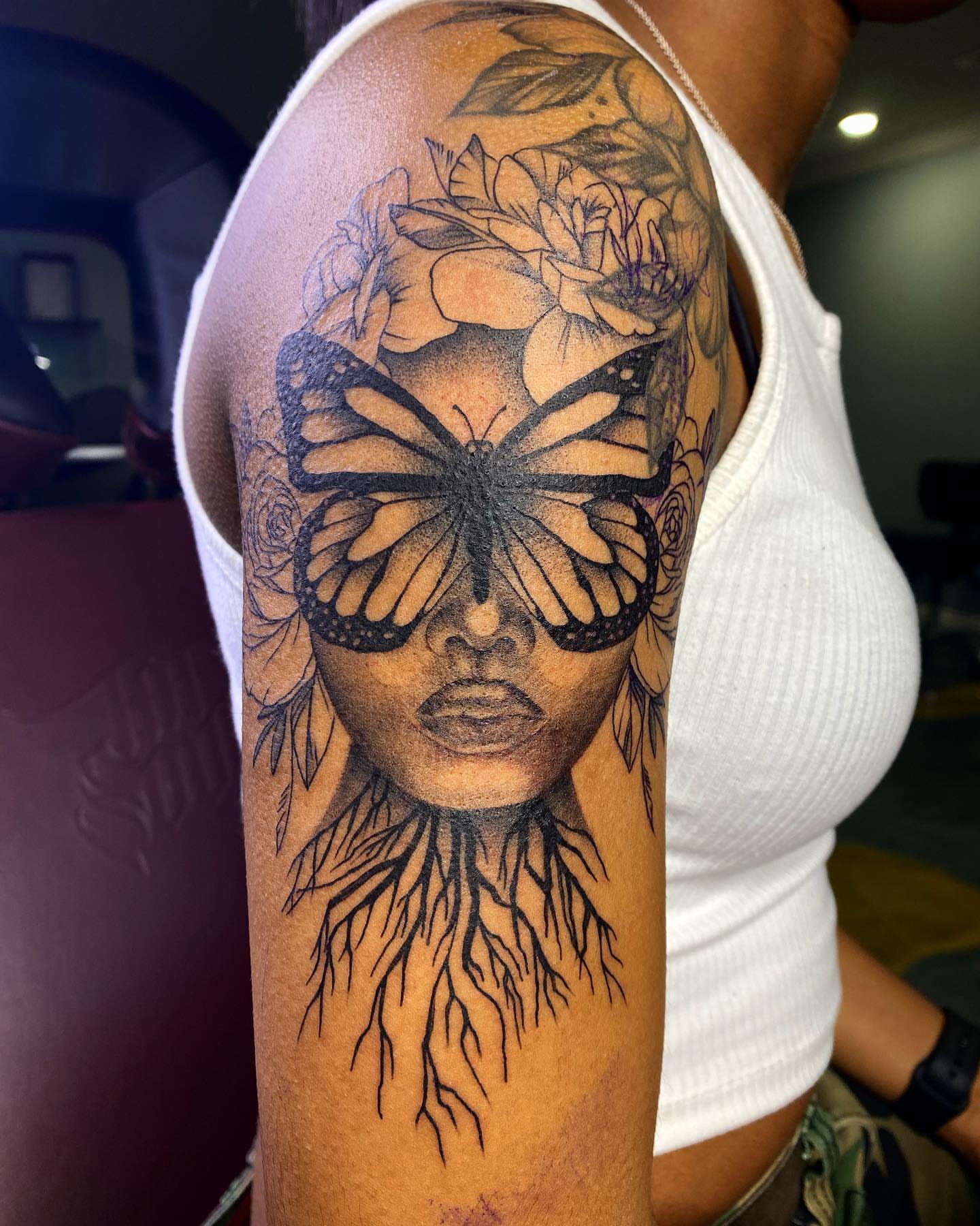Woman's face with butterfly realism tattoo on the forearm by Christopher Heffley