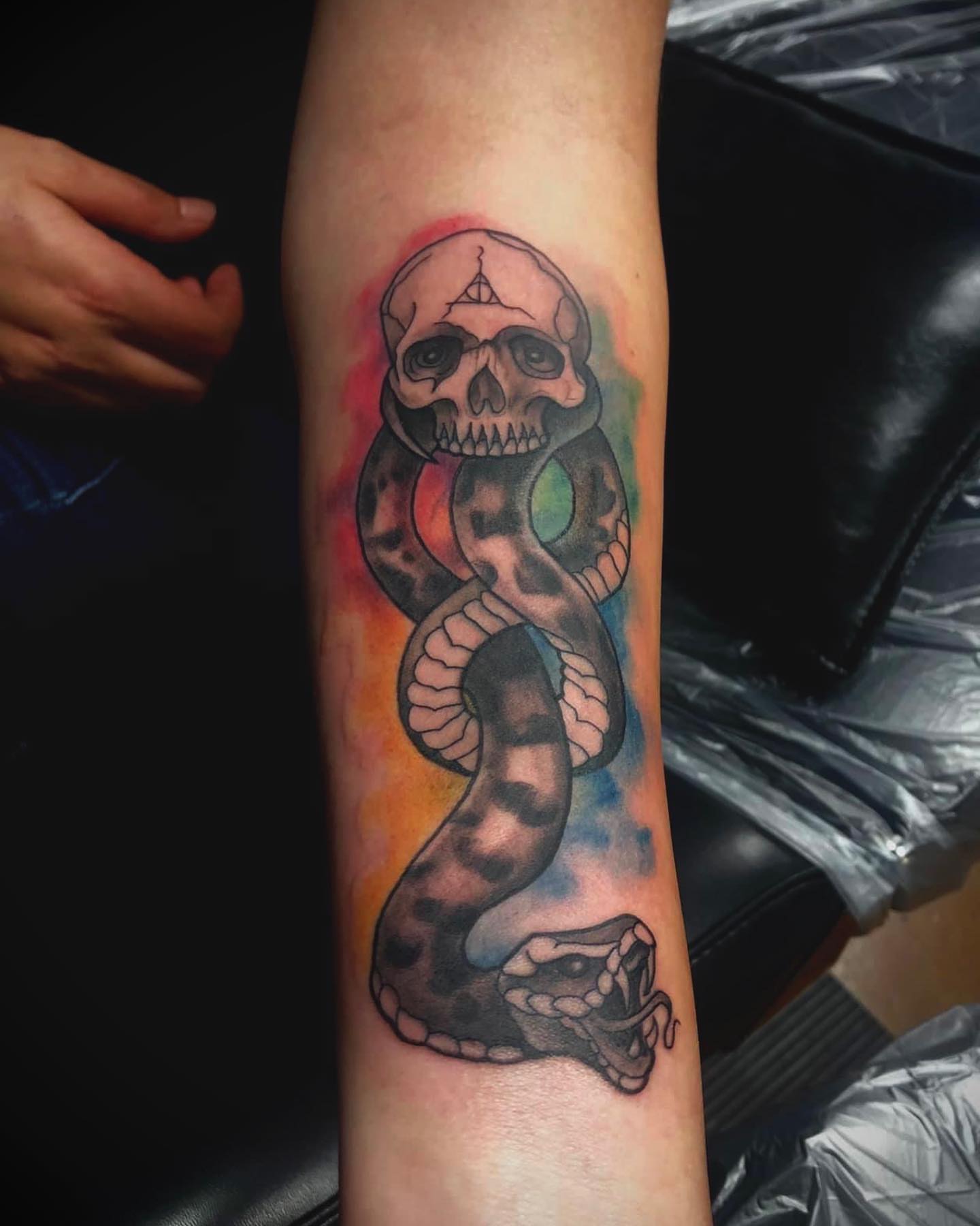 Snake and skull watercolor tattoo on the forearm by Tattoos by Dave