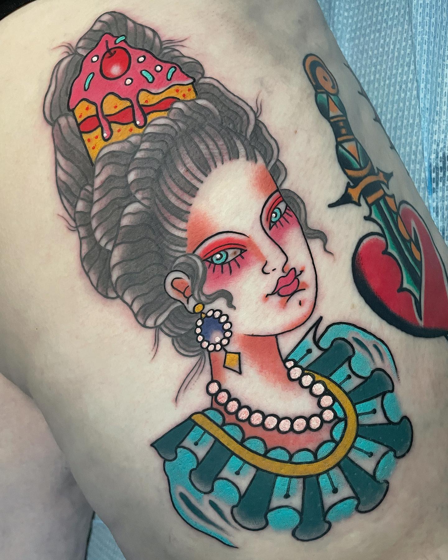 Woman with cake American traditional tattoo on the shoulder by Frank Mostek