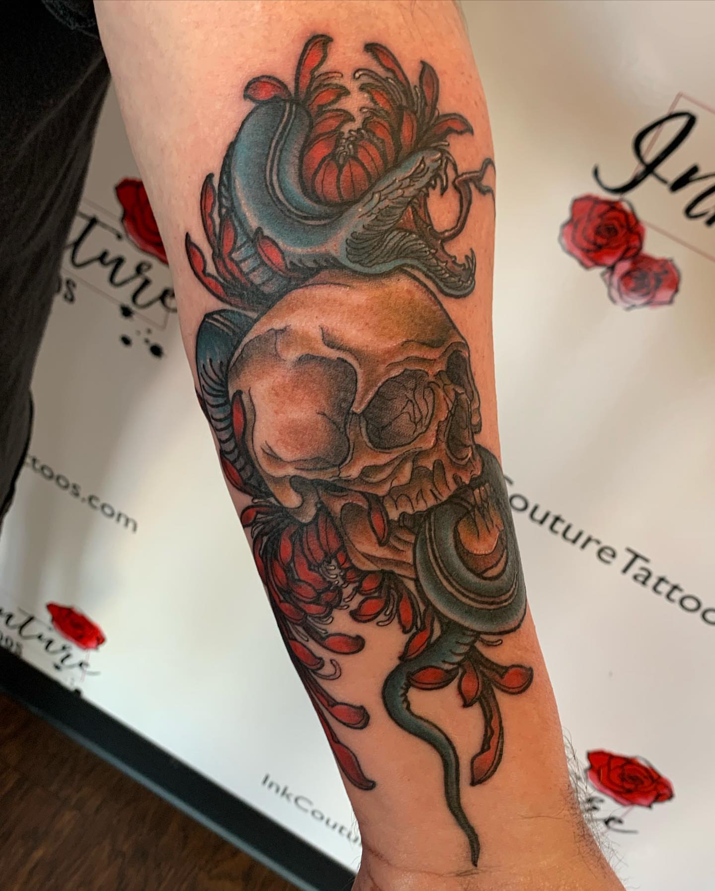 Skull with snake and flowers realism tattoo on the forearm by Justin James
