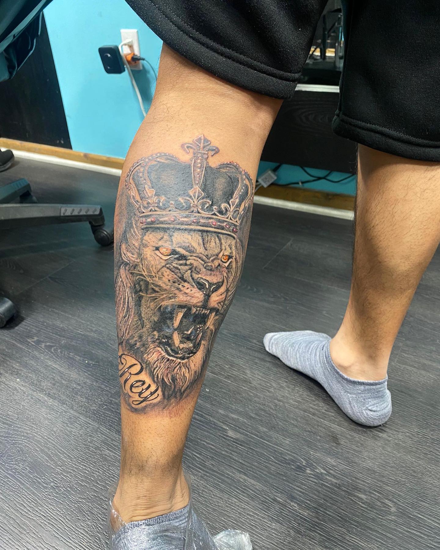 Lion with crown realism tattoo on the calf by Alberto Ramirez