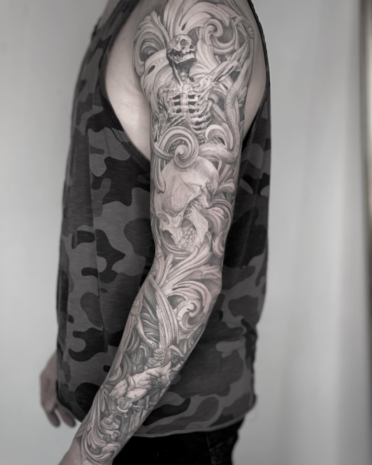Skeleton and swirling patterns realism tattoo on the upper arm by Paige Jean