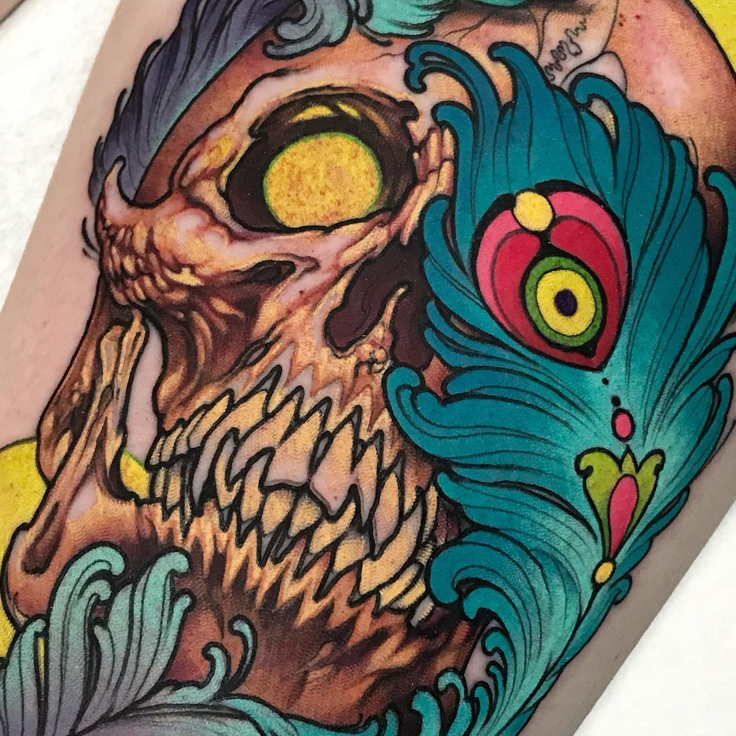 Skull with peacock feather American traditional tattoo on the forearm by Alisha Harding