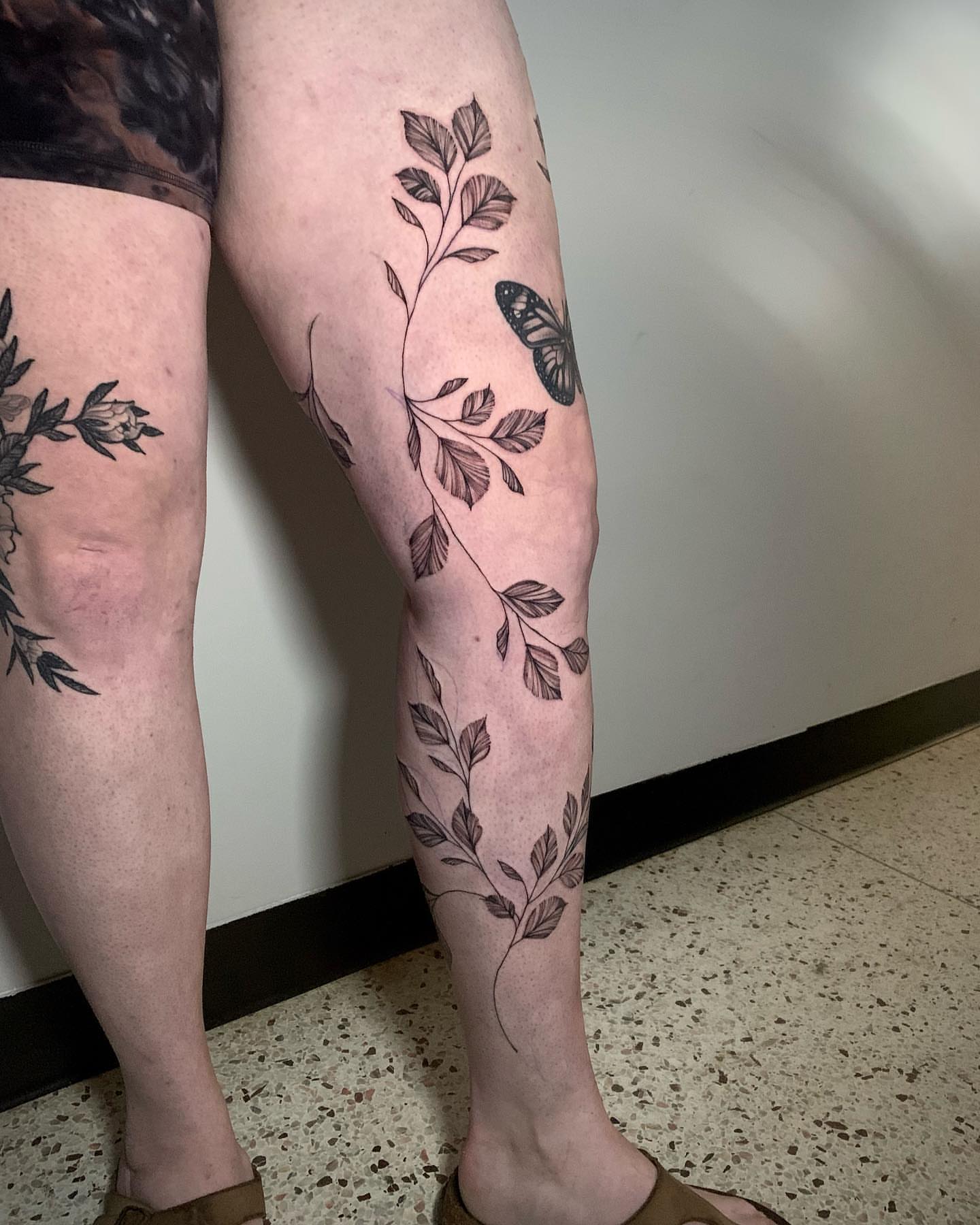 Plant and butterfly black and grey tattoo on the calf by Megan McKee Tattoo Artist